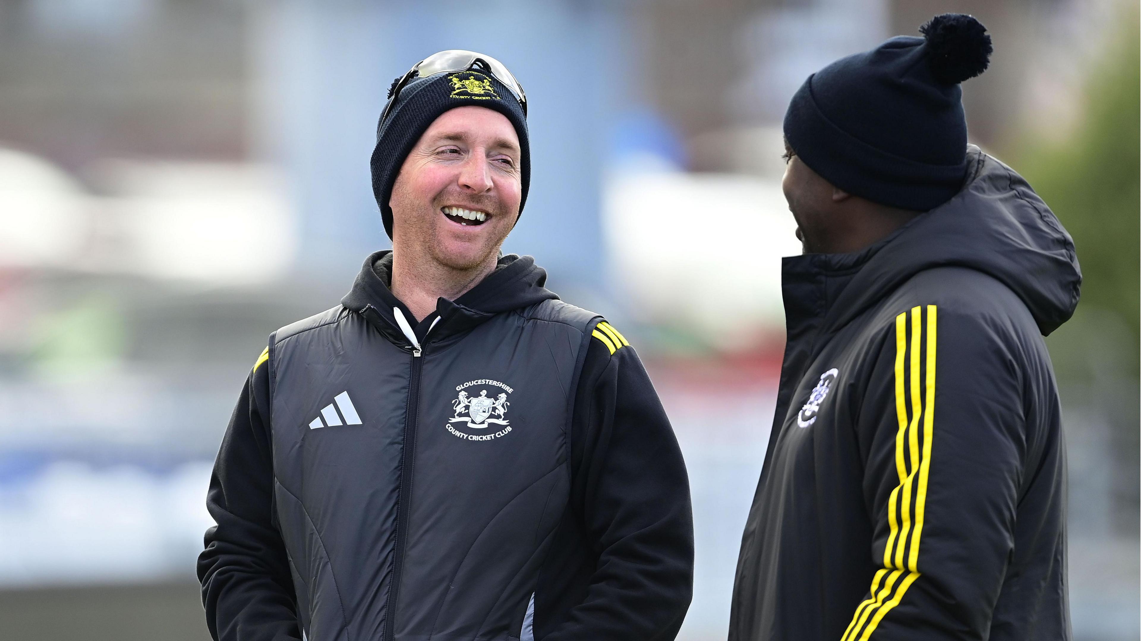 Tom Smith (left) stands with his hands in his pockets and laughs with head coach Mark Alleyne next to him