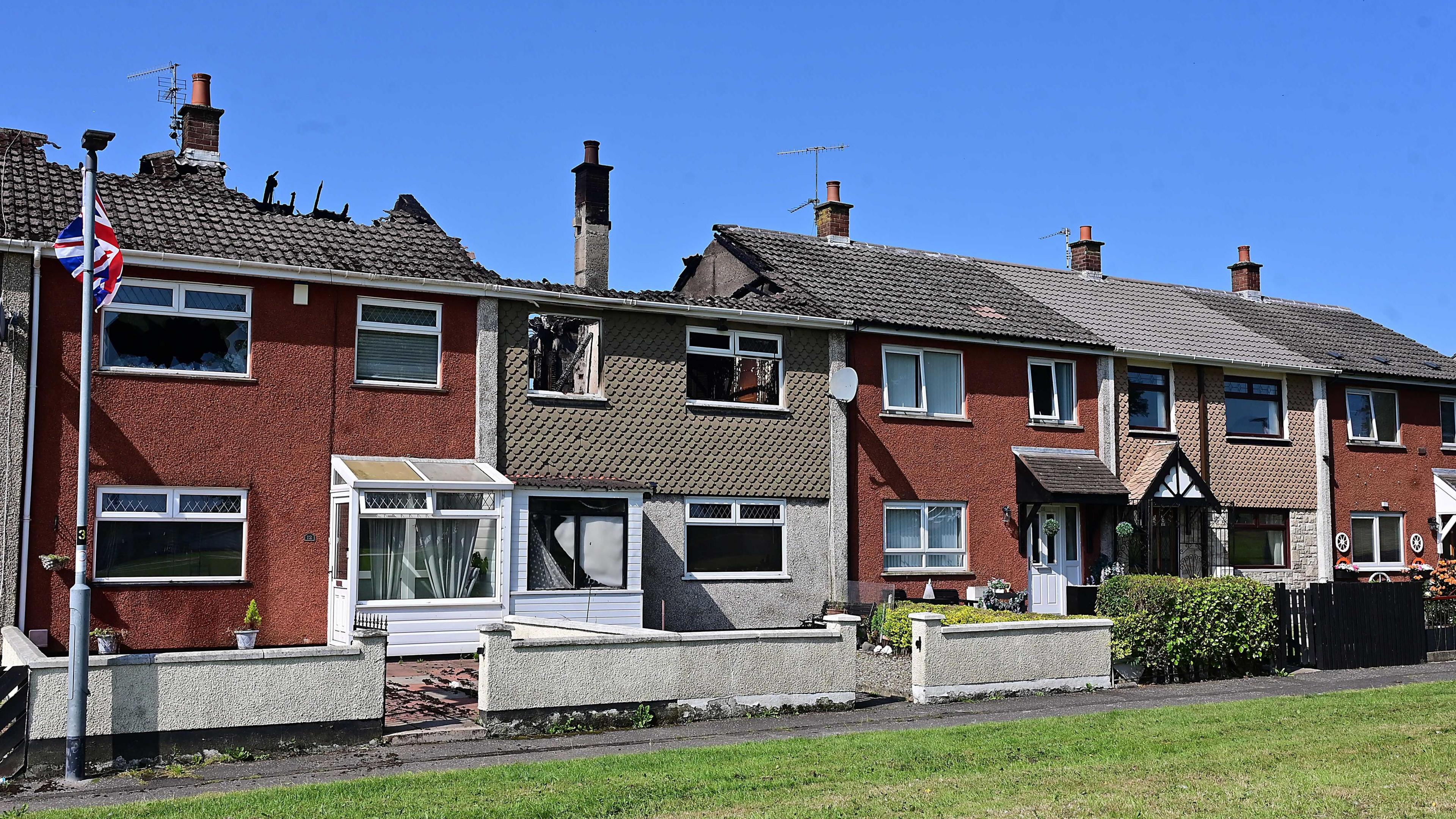 A row of terraced houses, two showing fire damage with roofs partially missing