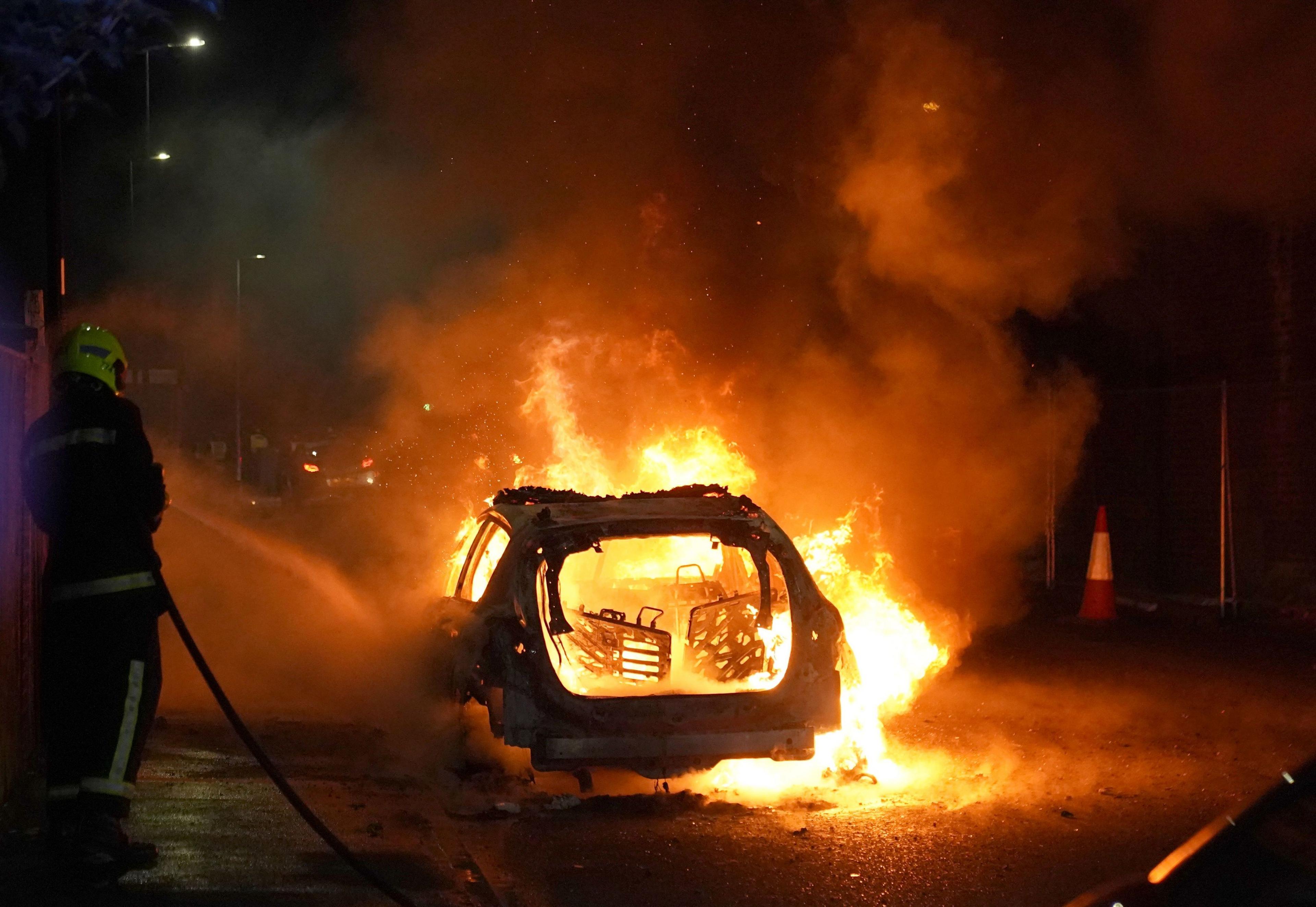 Burning car being attended to by firefighters