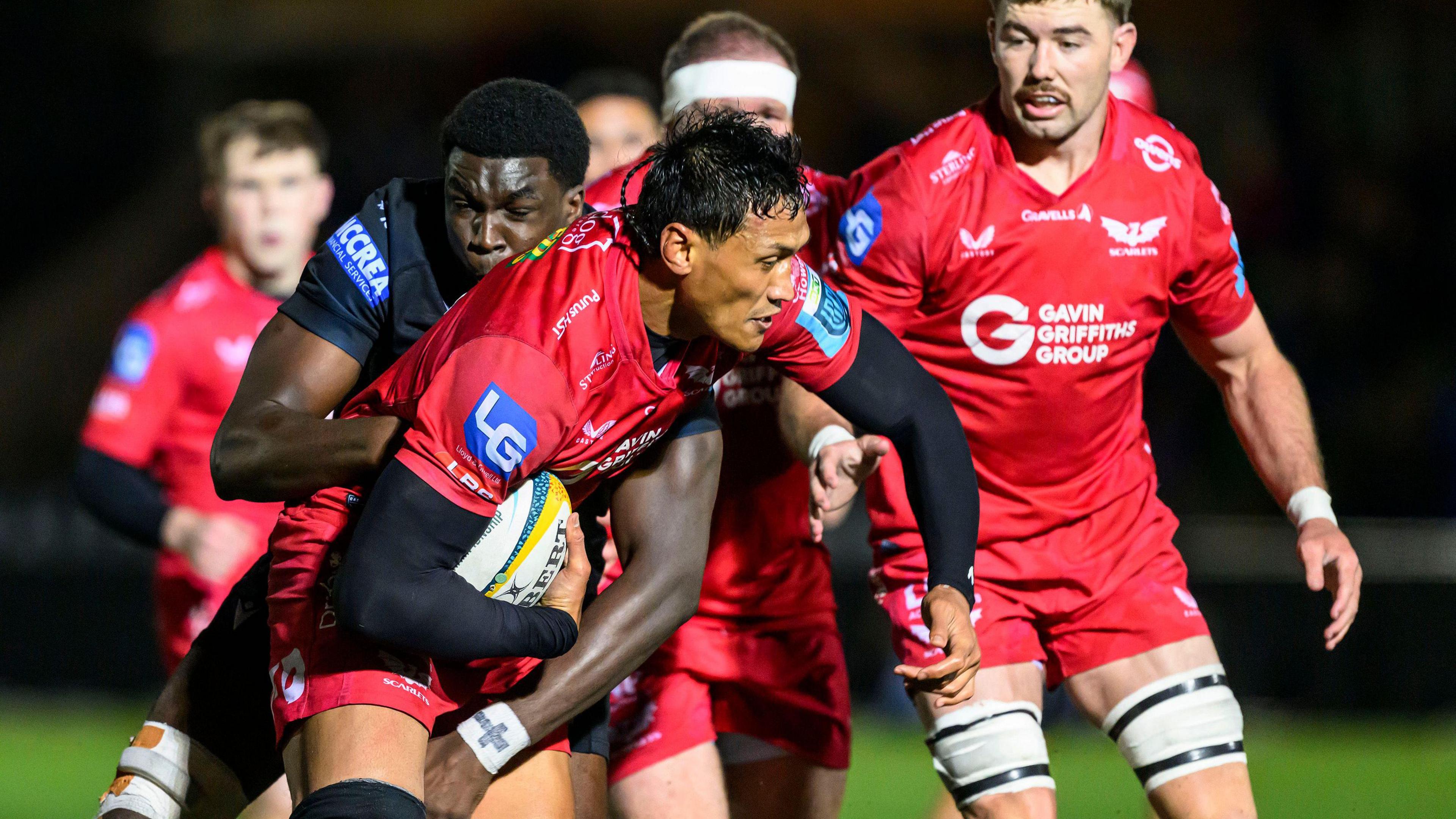 Sam Lousi of Scarlets is tackled by Jare Oguntibeju of Glasgow