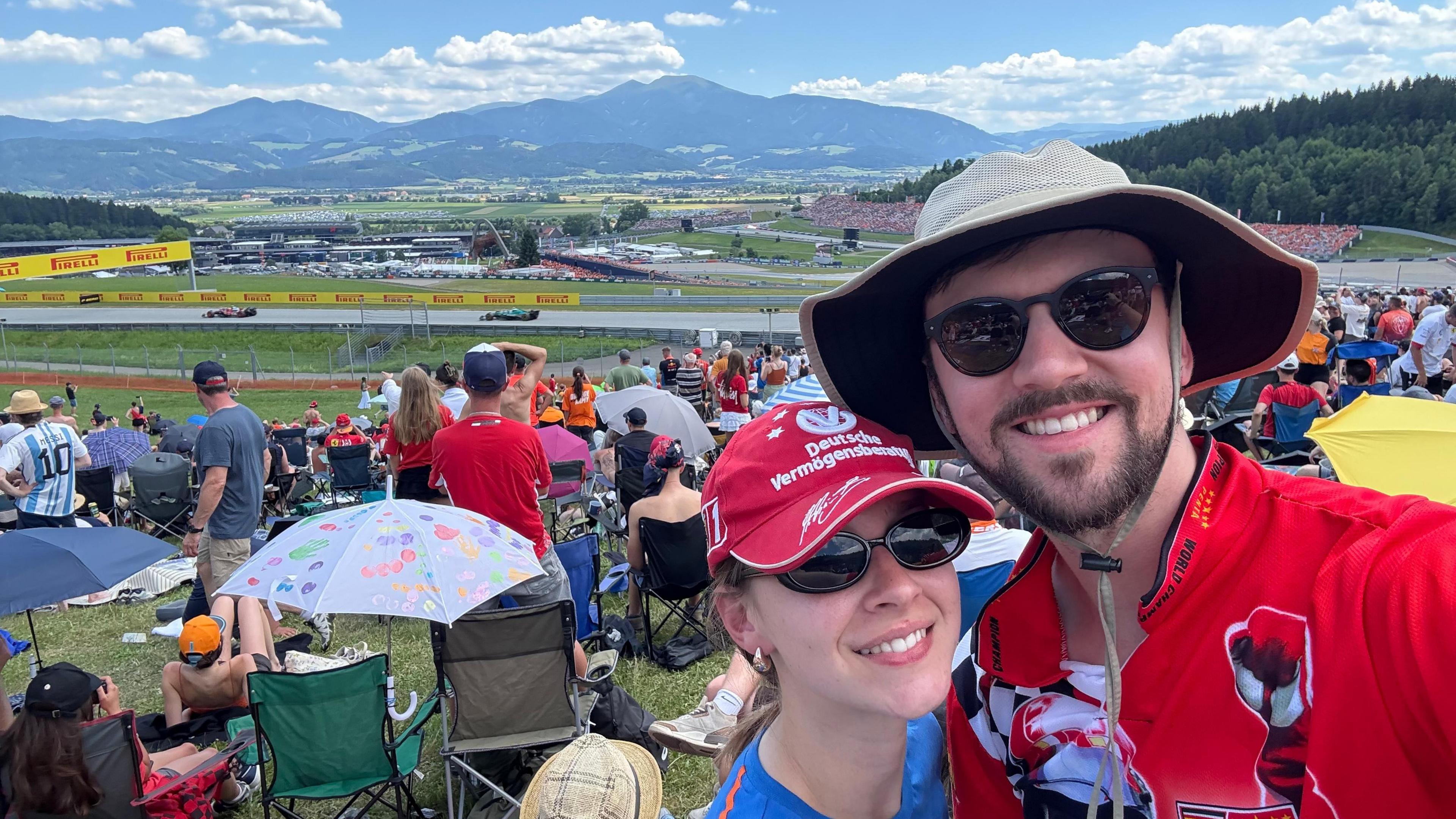 Brandon Burgess poses for a selfie at the Austrian Grand Prix at the Red Bull Ring, with the Styrian Mountains in the backgrounds