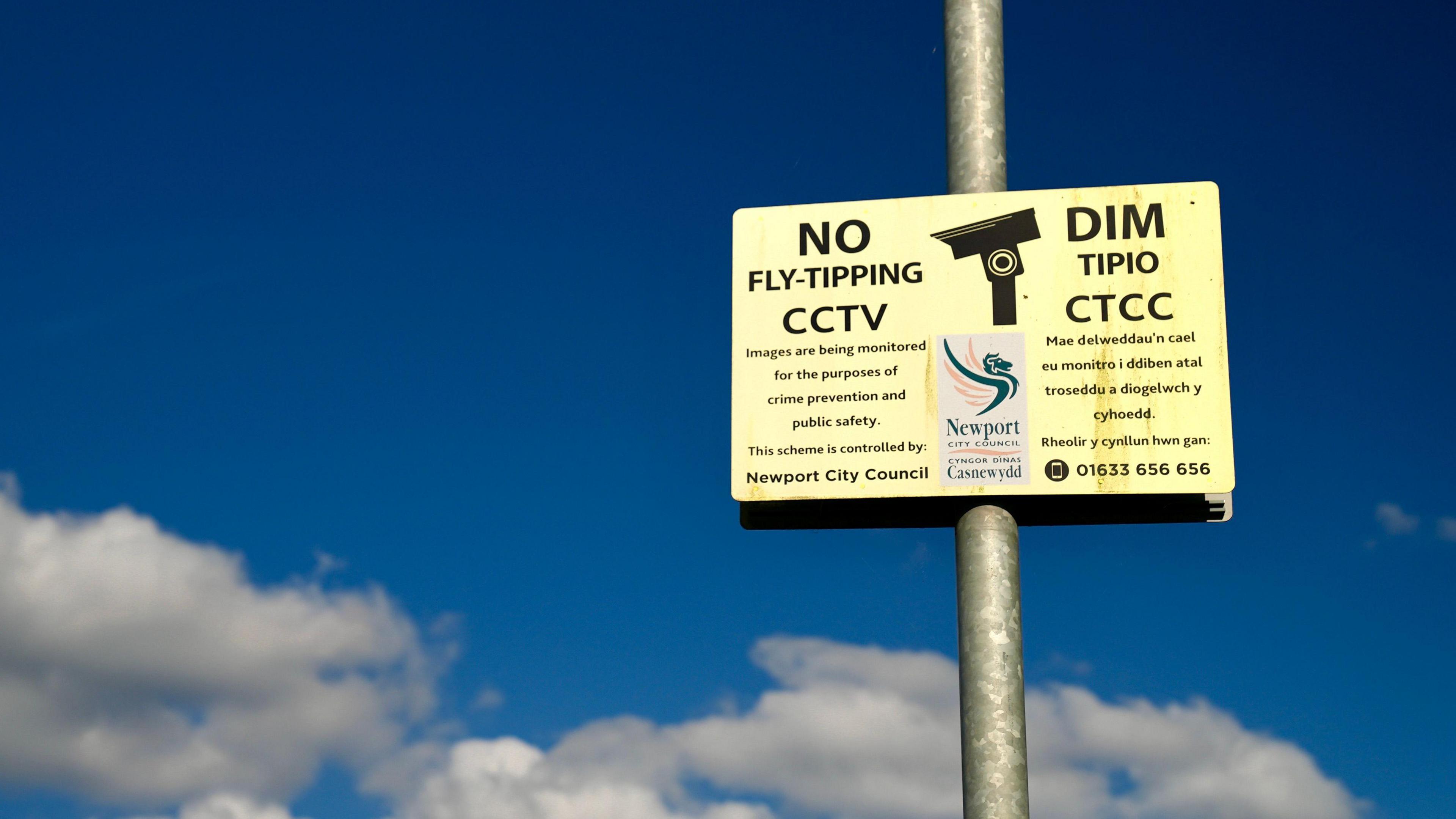 A picture of a council sign, depicting a CCTV camera - the sign says, "No fly-tipping, CCTV" - In English and Welsh.