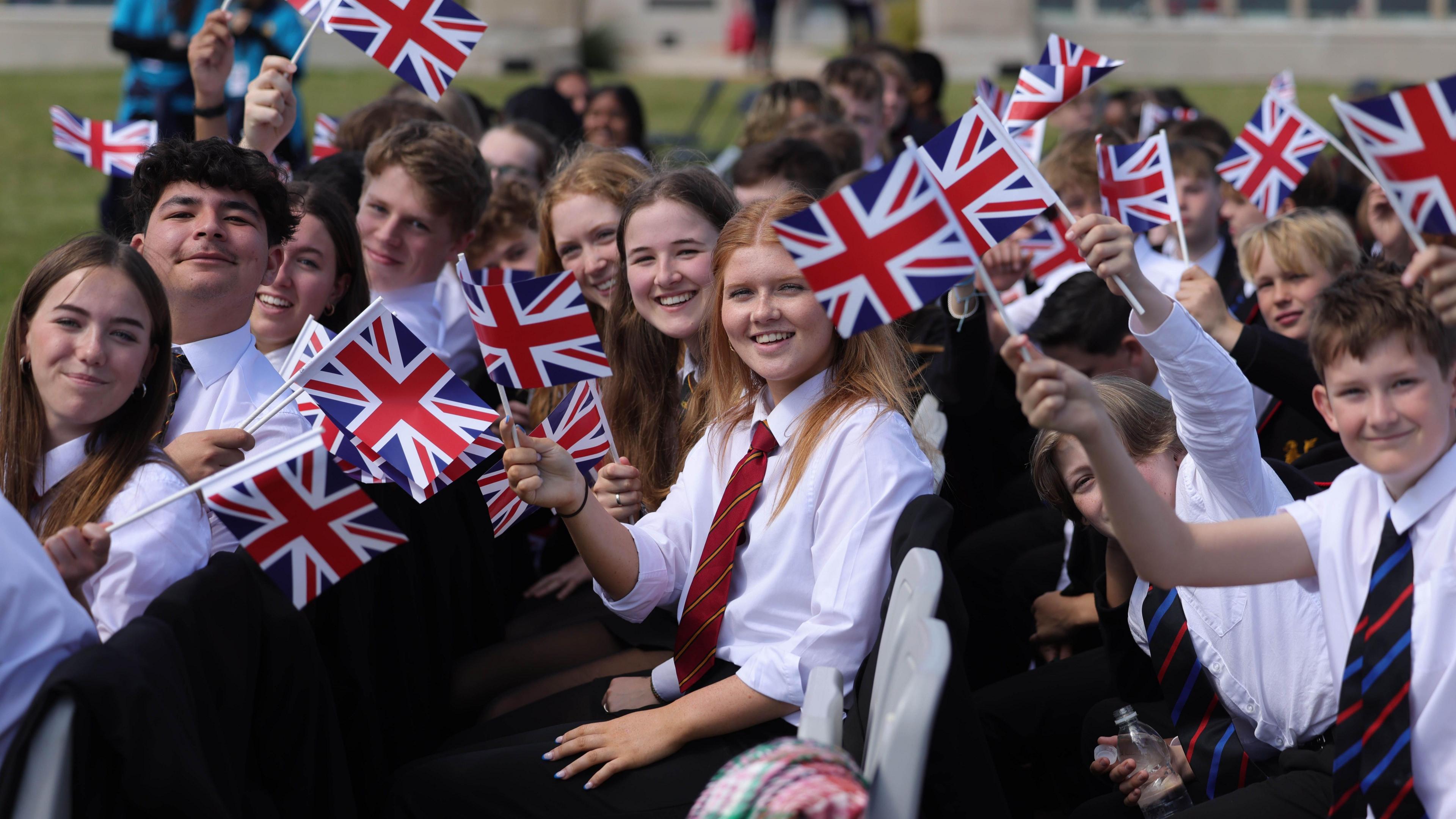 Schoolchildren waving flags from the audience at Portsmouth