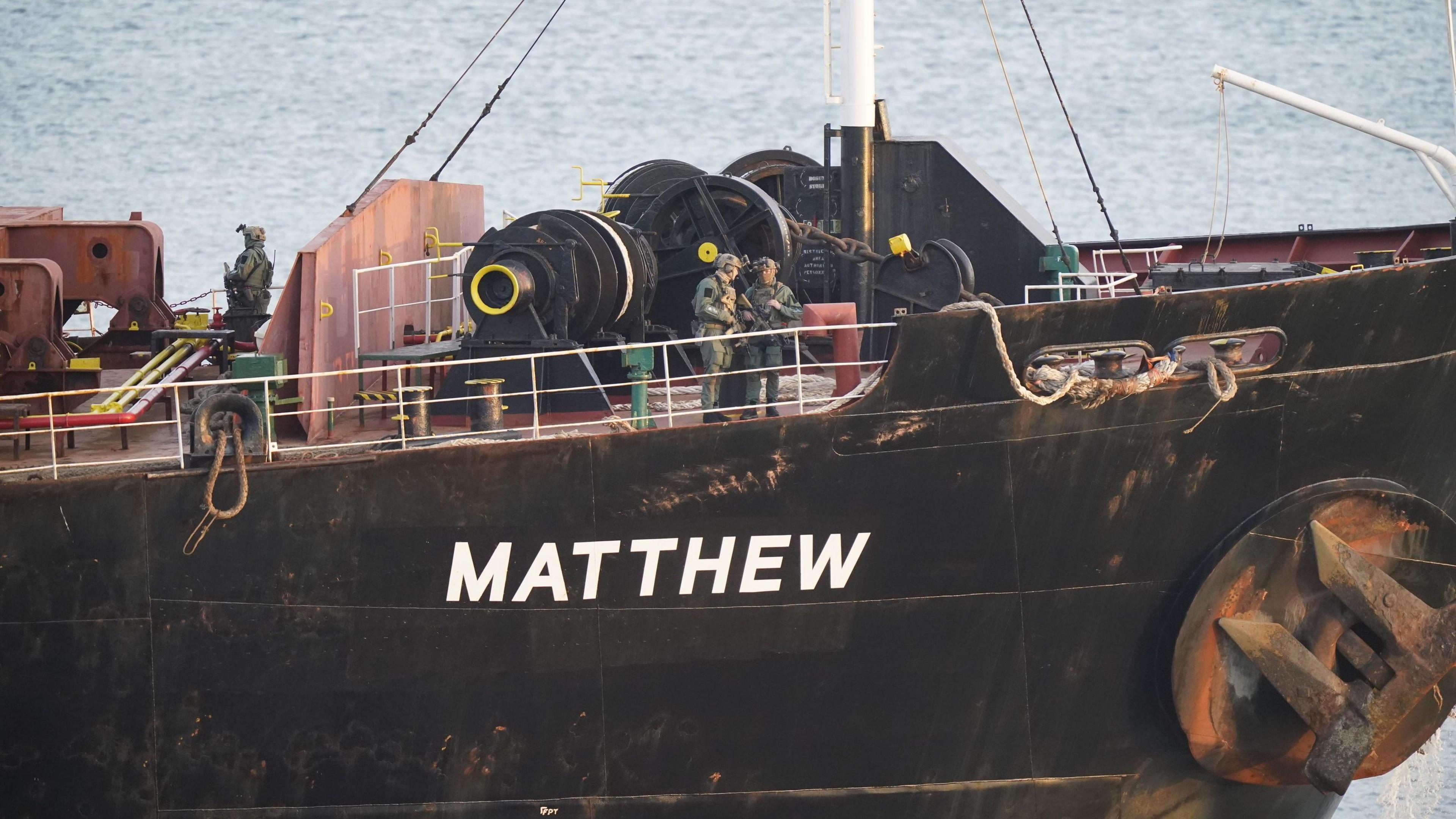 Black boat with Matthew in white text, military personnel pictured onboard deck