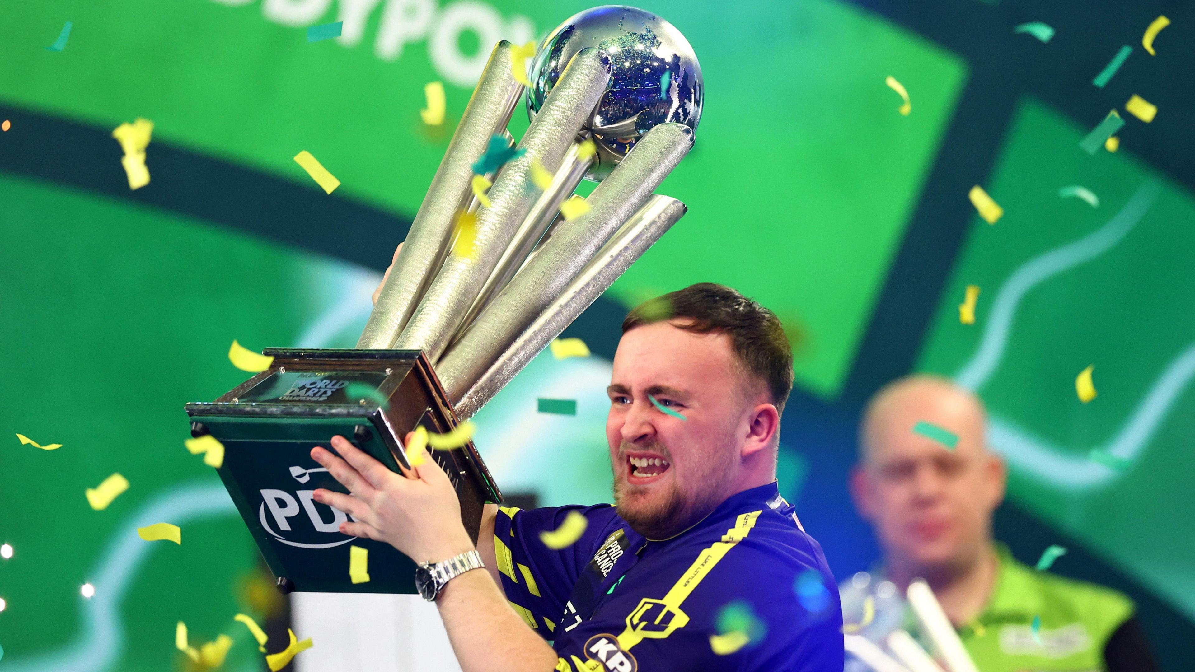 Luke Littler lifting darts world championship trophy 