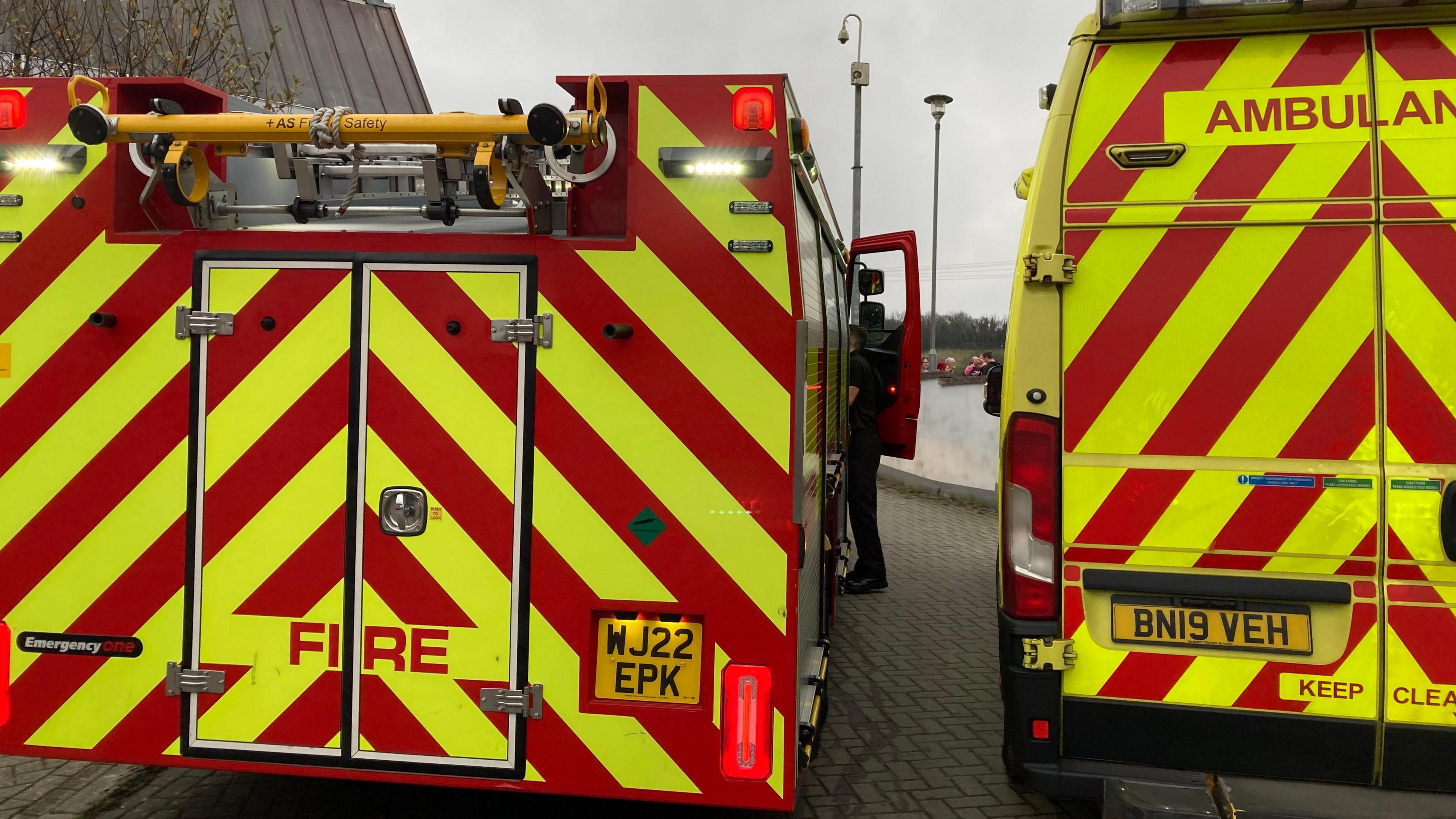 The back of a fire engine and an ambulance. Both have red and yellow chevrons on the back.