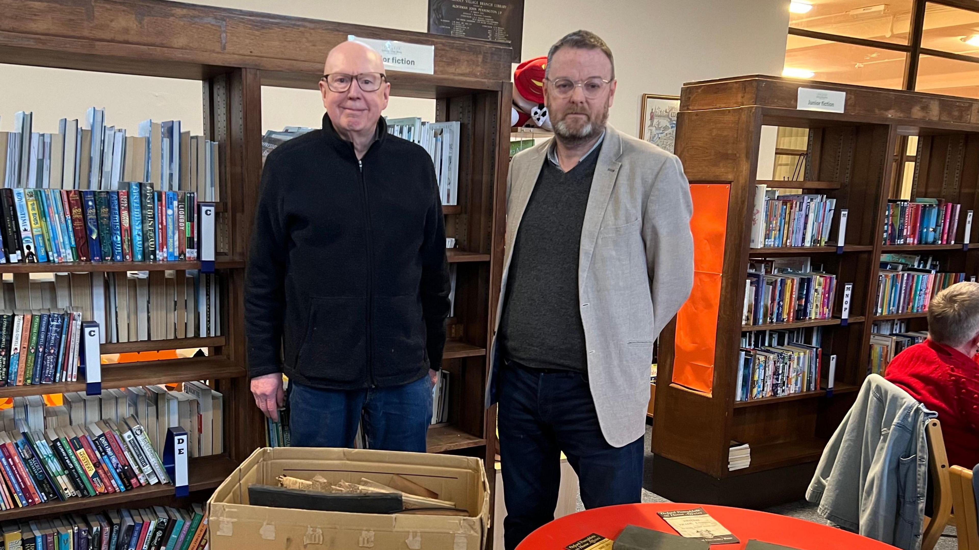 Ray Lyons with councillor Ian Lewis standing in the library by the artefacts 