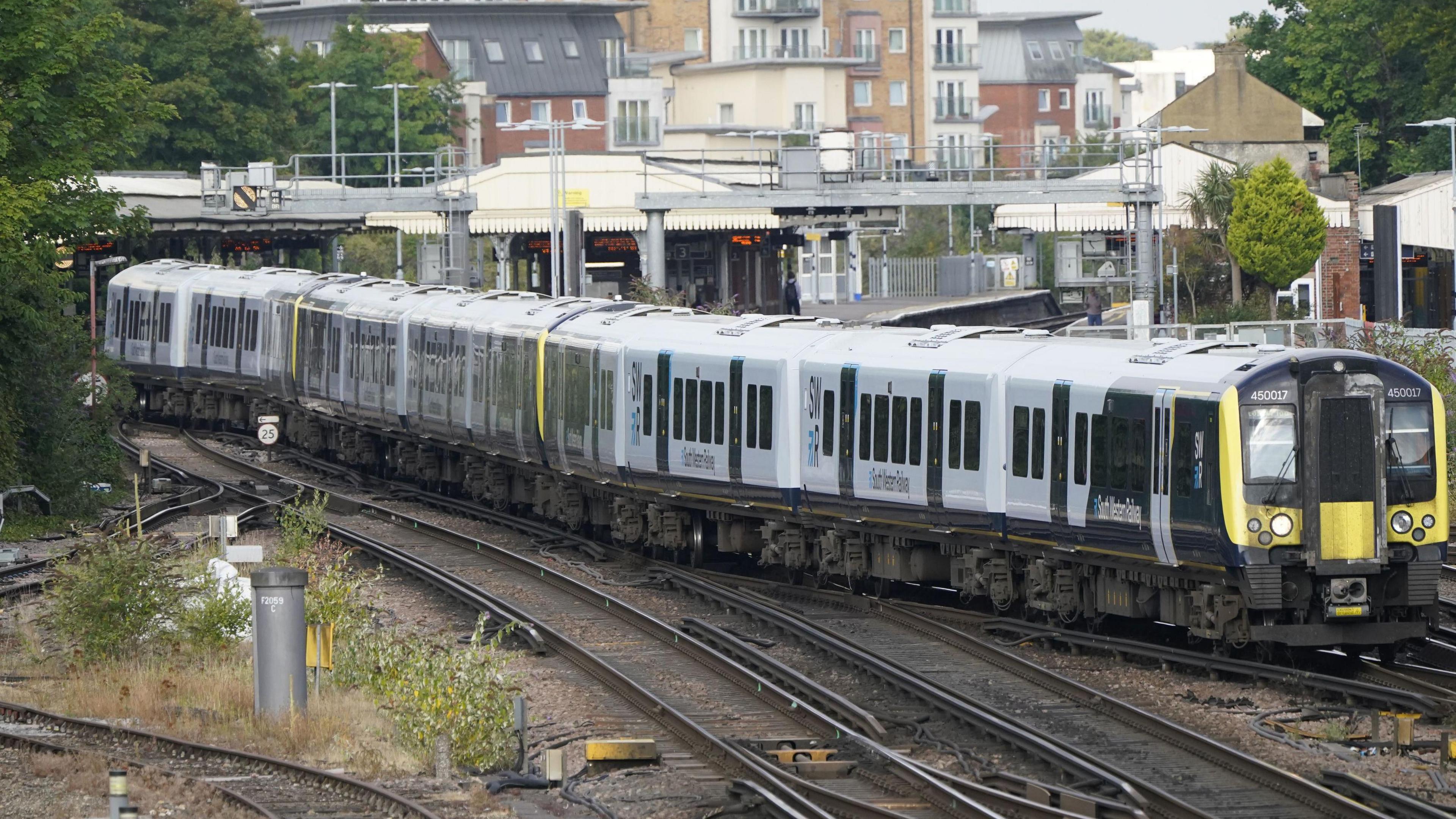 A blue and white South Western Railway train leaves Basingstoke station.