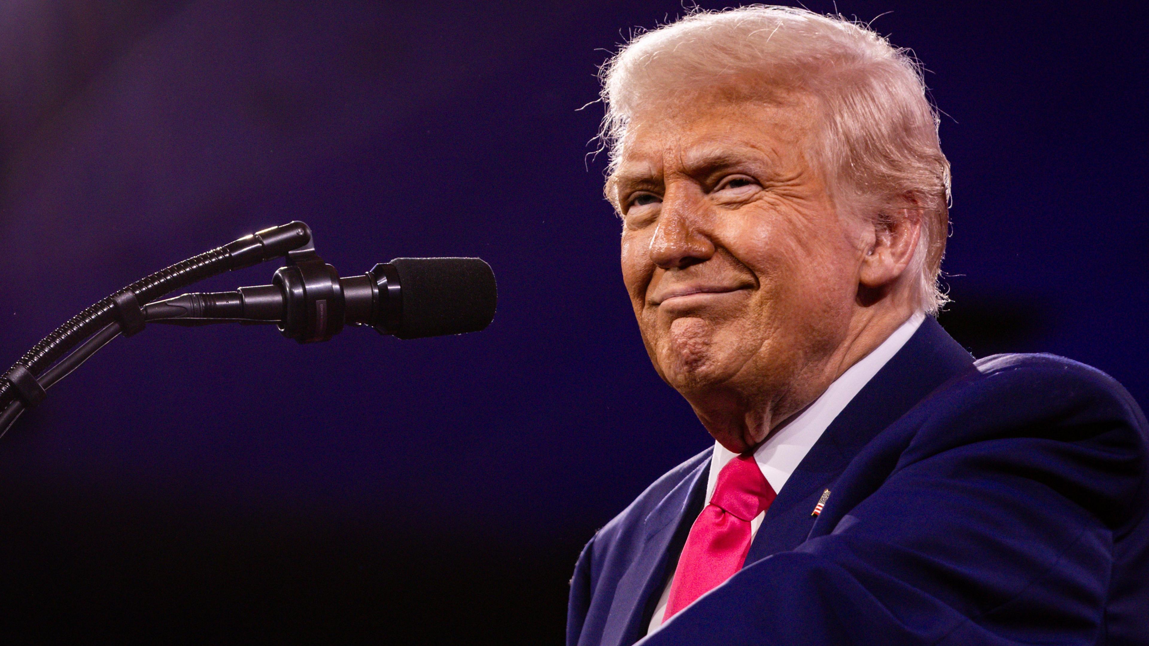 US President Donald Trump speaks on the last day of the annual Conservative Political Action Conference. He is wearing a navy blue blazer with a white shirt and red tie