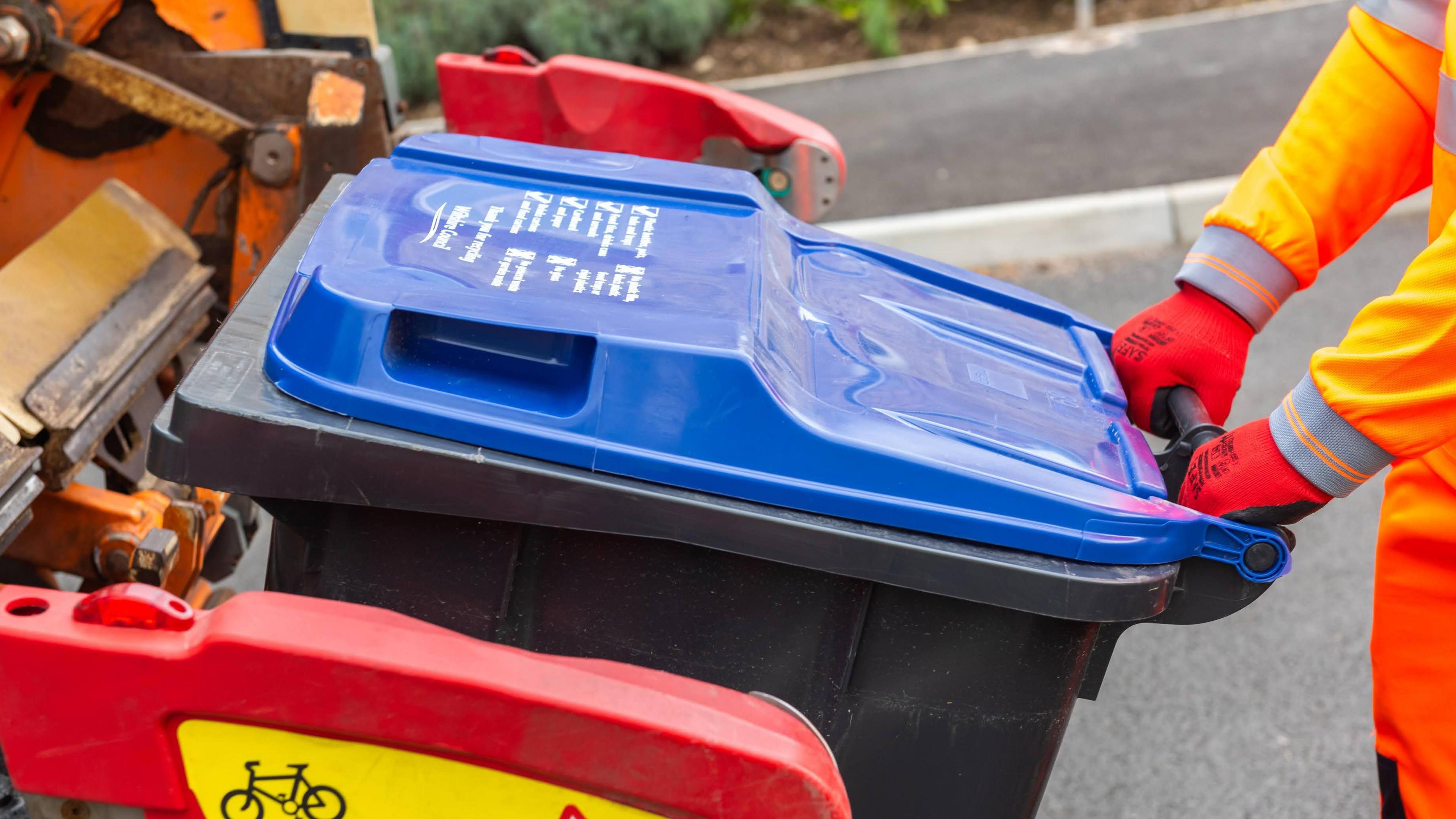 Black bin being collected on collection day.