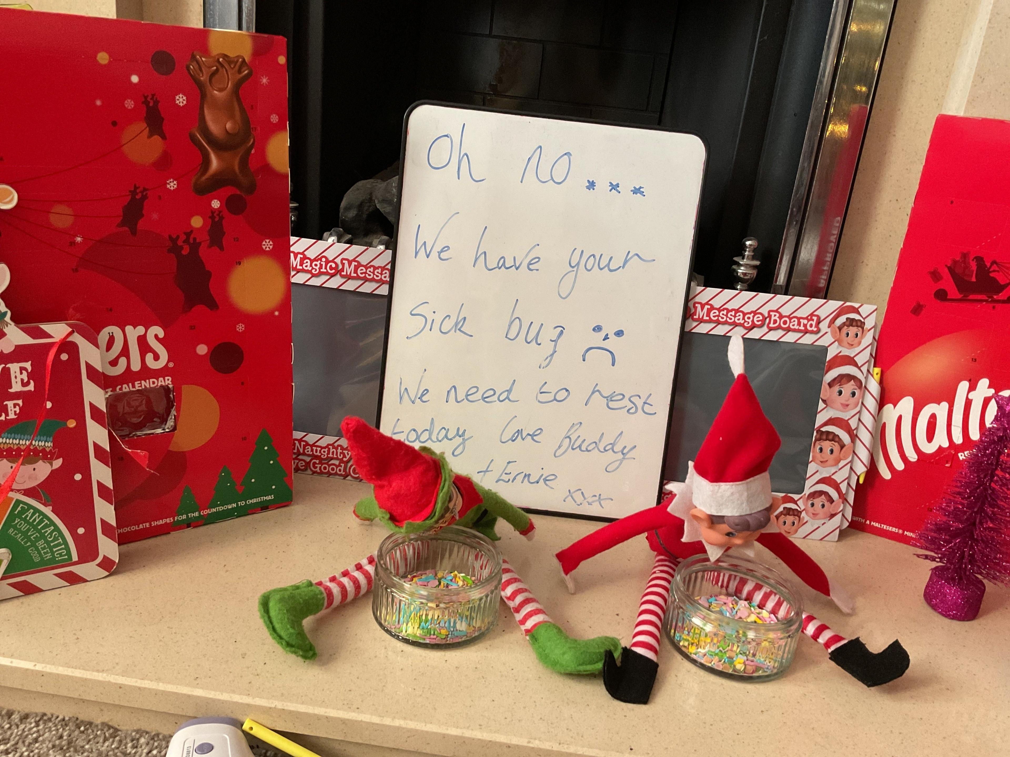 Advent calendars can be seen with a small whiteboard in front which reads "oh no we have your sick bug. We need to rest today. Love Buddy and Ernie. 