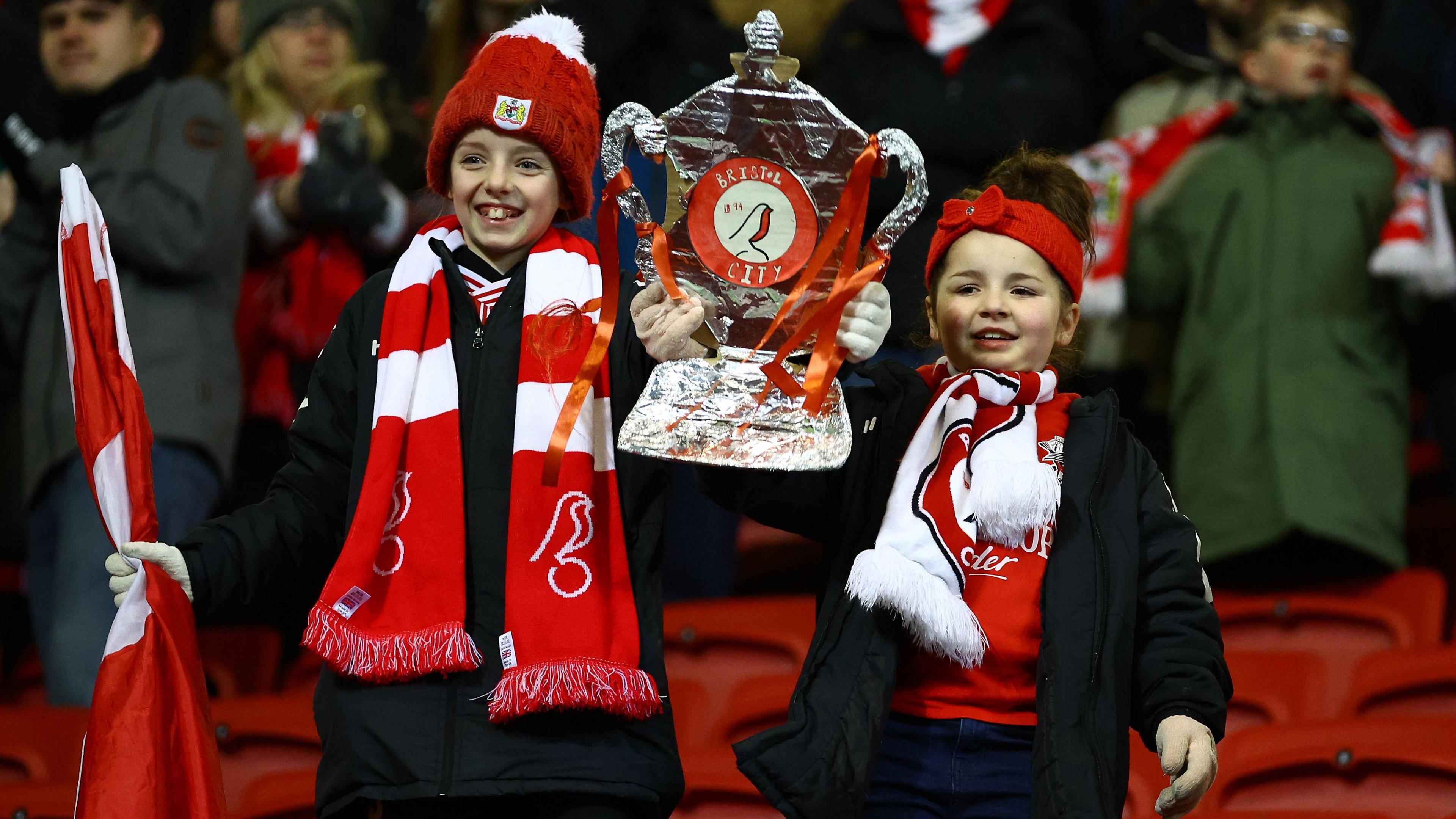 Young Bristol City fans hold a tin foil FA Cup in the stands