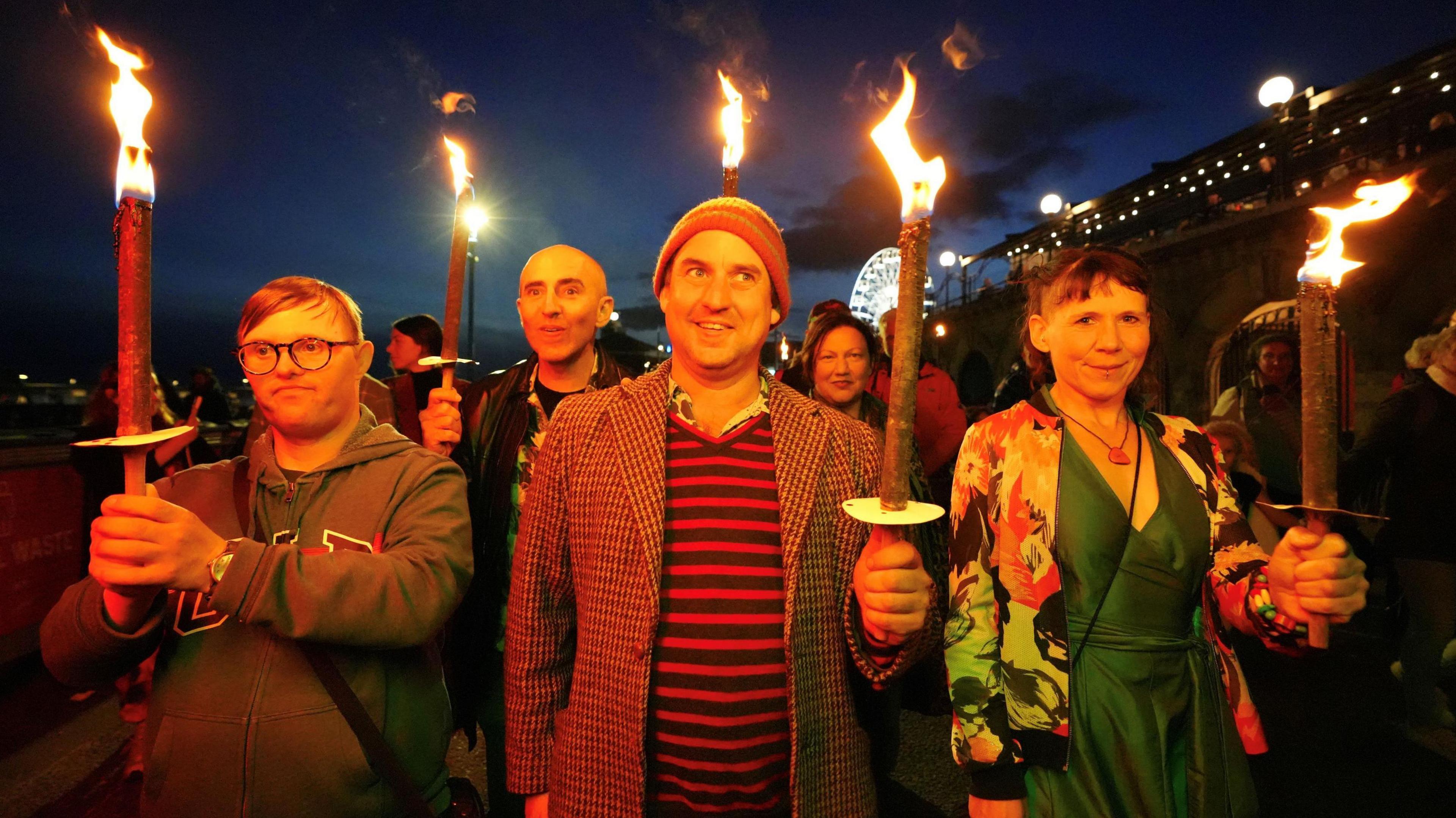 A candlelit trail with people walking with candles