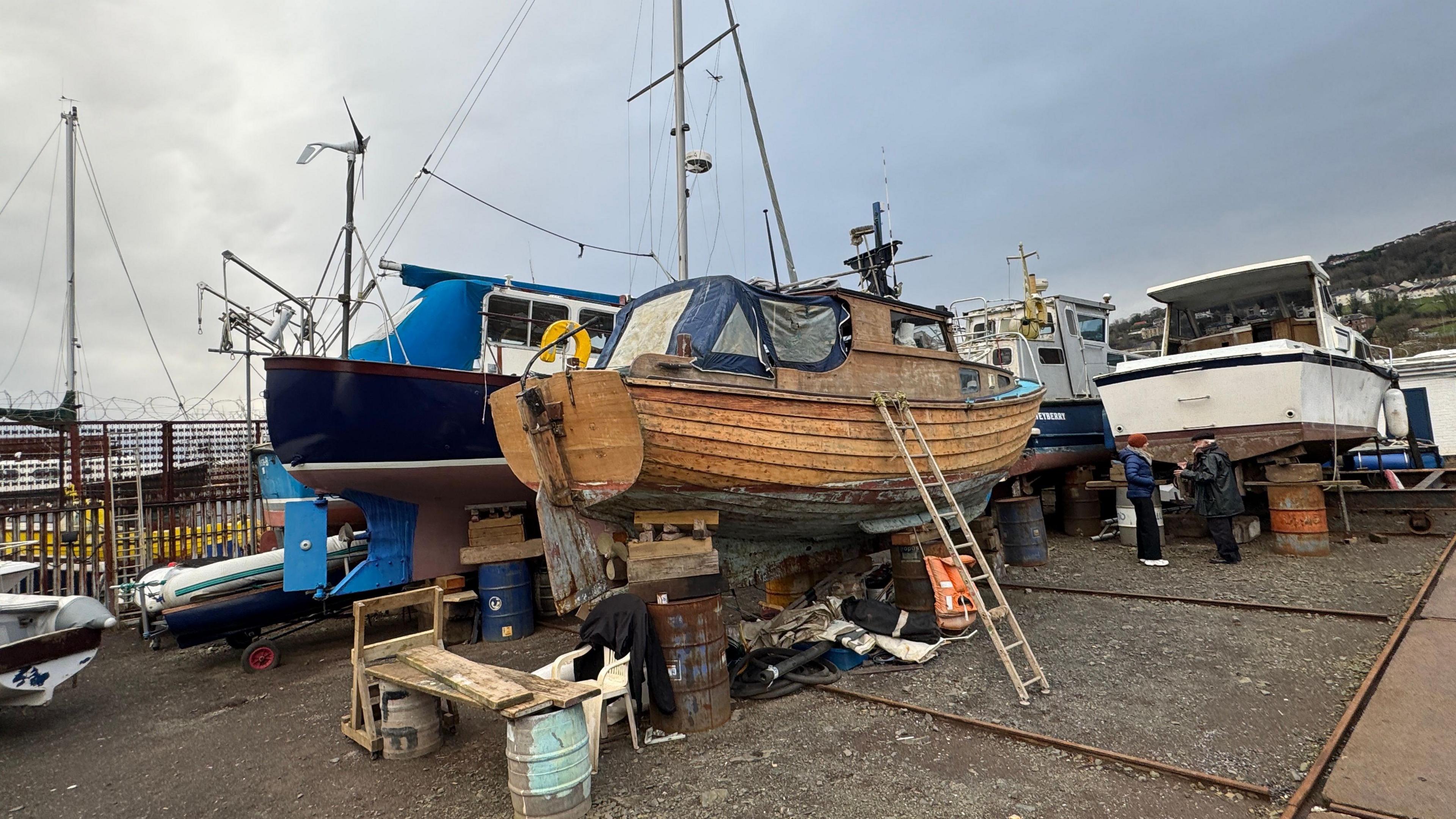 Boat yard with small fishing boats, surrounded by a wire fence