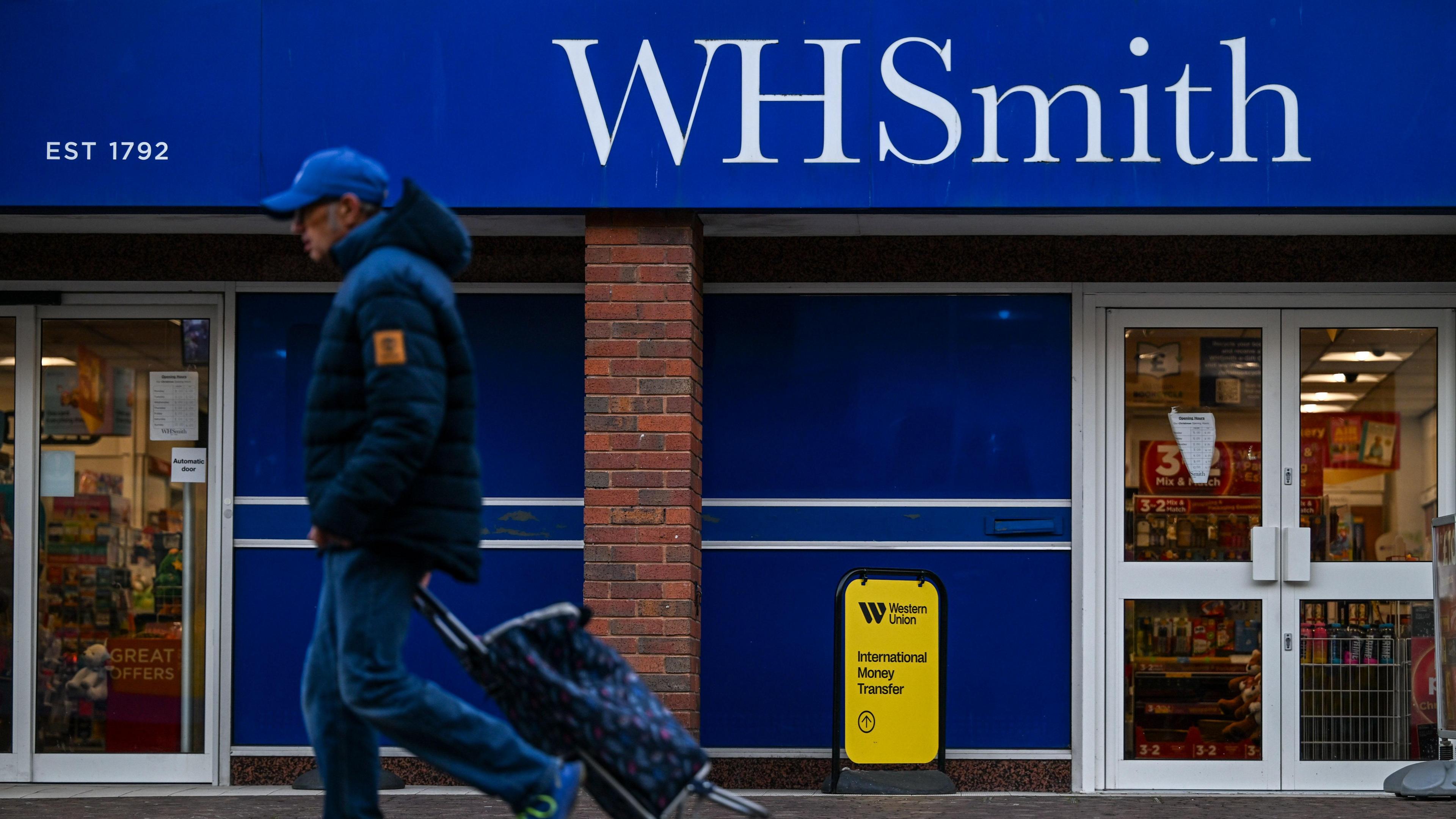 A man walks past a WH Smith store, which displays a sign "established 1792"