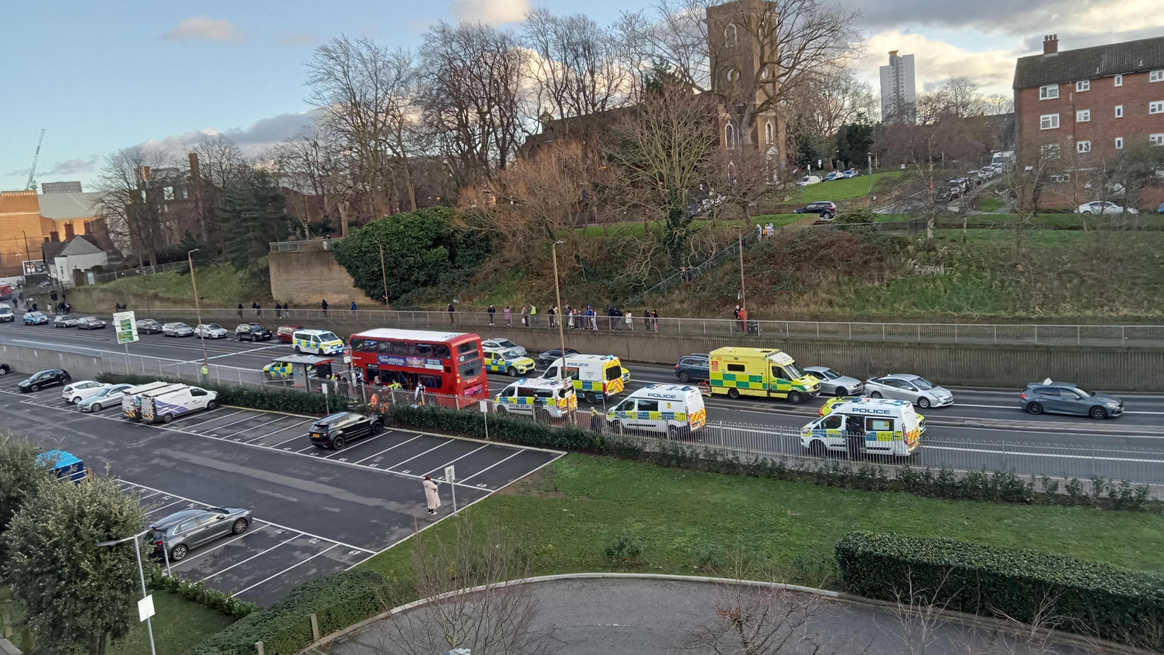 Wide amateur shot of the stationary bus after the attack, surrounded by emergency vehicles