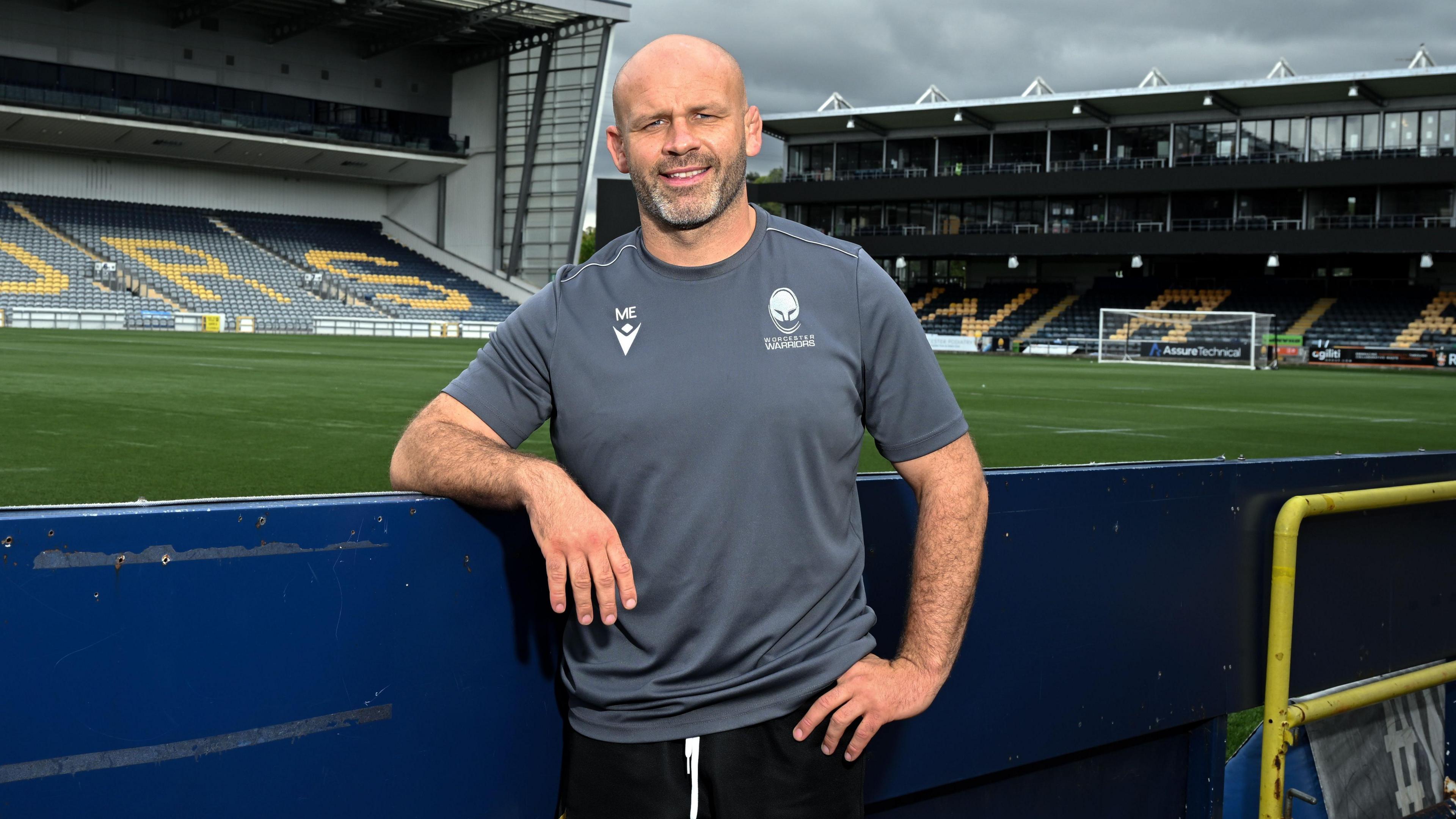 Worcester Warriors head coach leans on a hoarding at Sixways