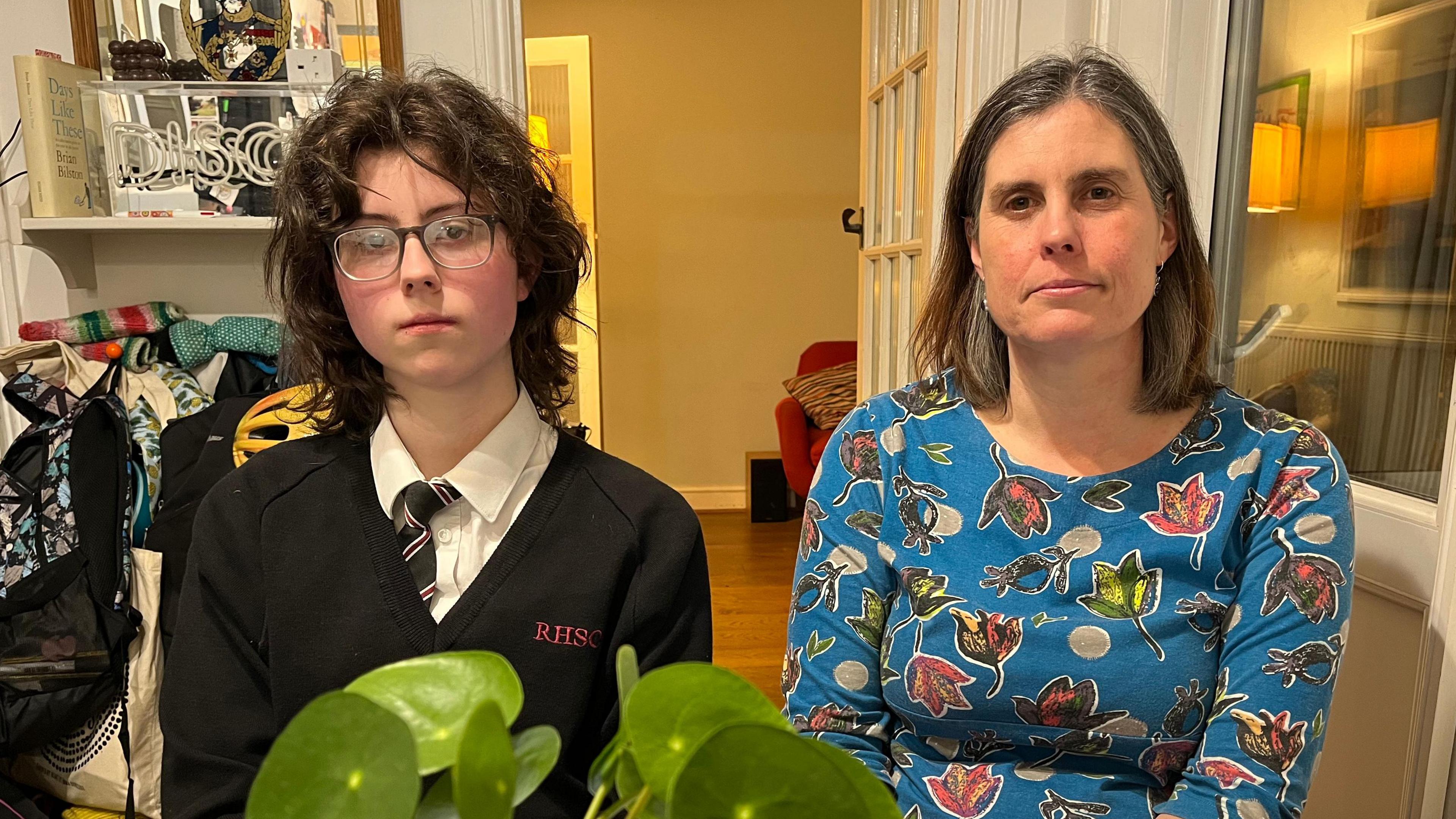 Martha sitting at the kitchen table with her mother, Karen. A leafy, green plant sits on the table in the foreground.