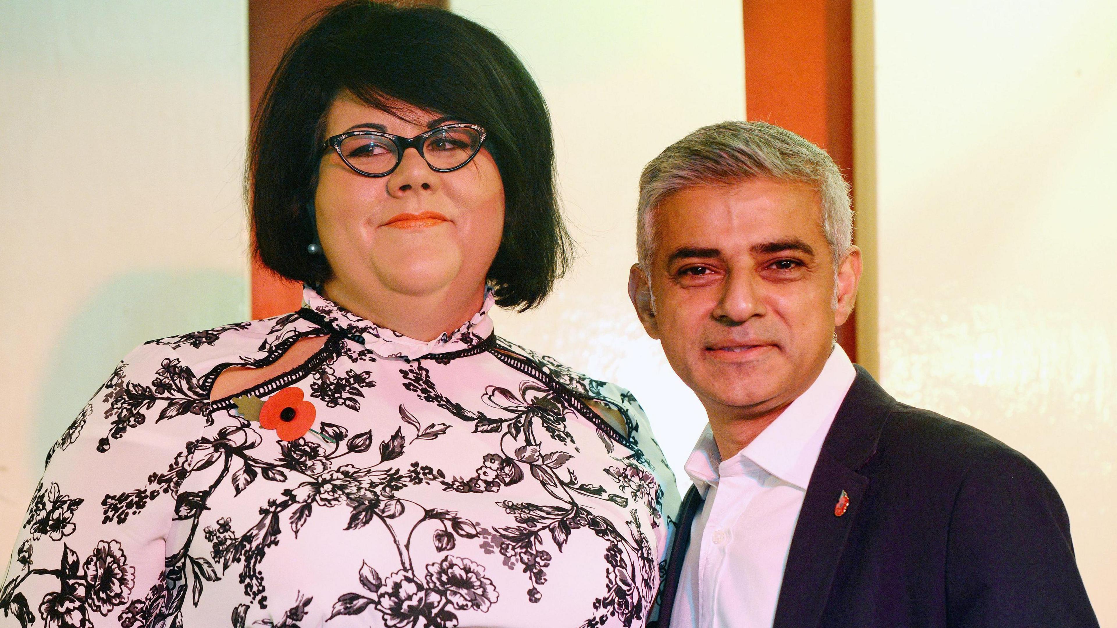 Amy Lame, a black haired woman in a black and white dress, stands next to the mayor of London who is wearing a black suit jacket and a white shirt. 