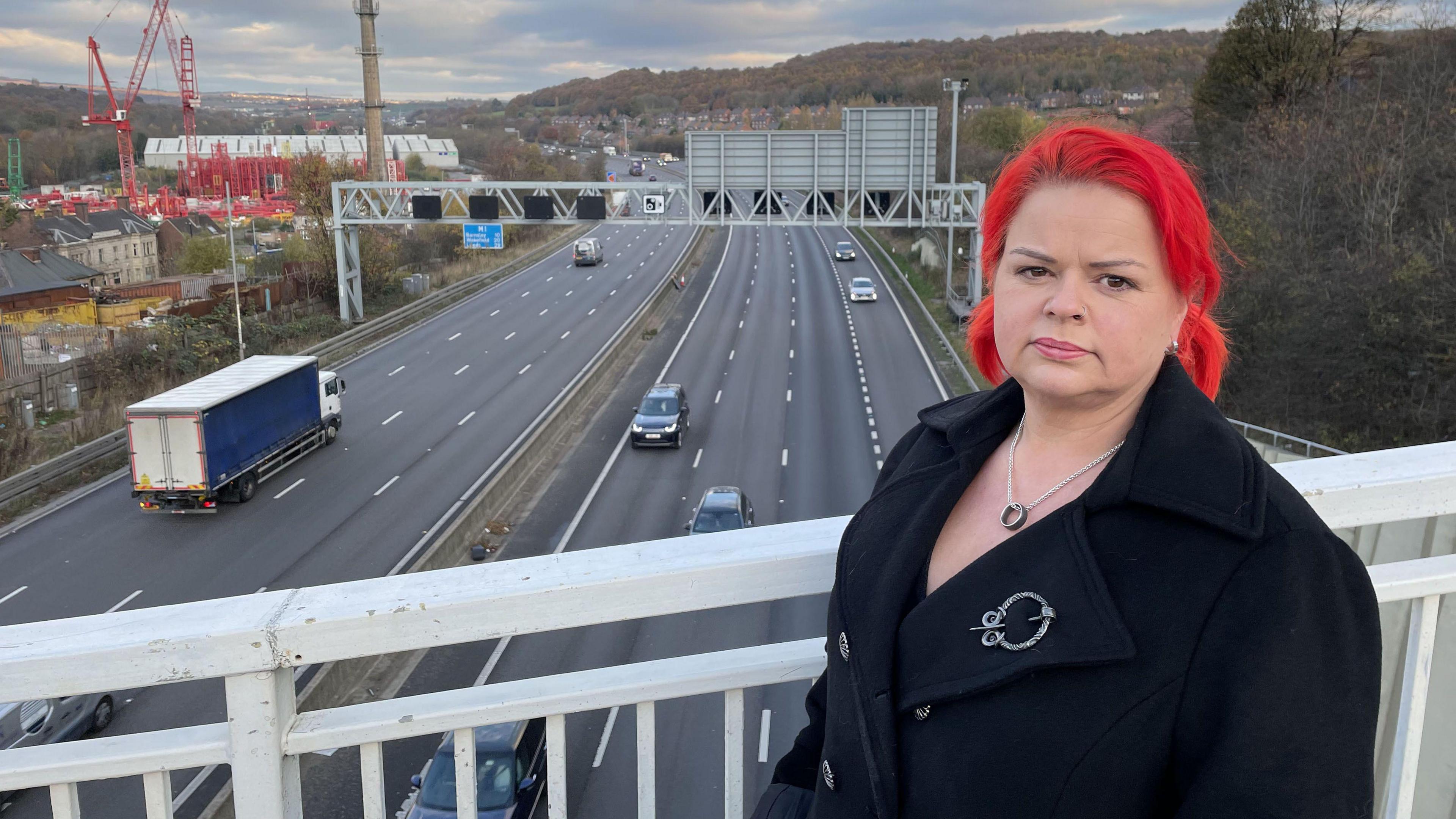 Claire Mercer standing on a bridge that looks over a smart motorway. 