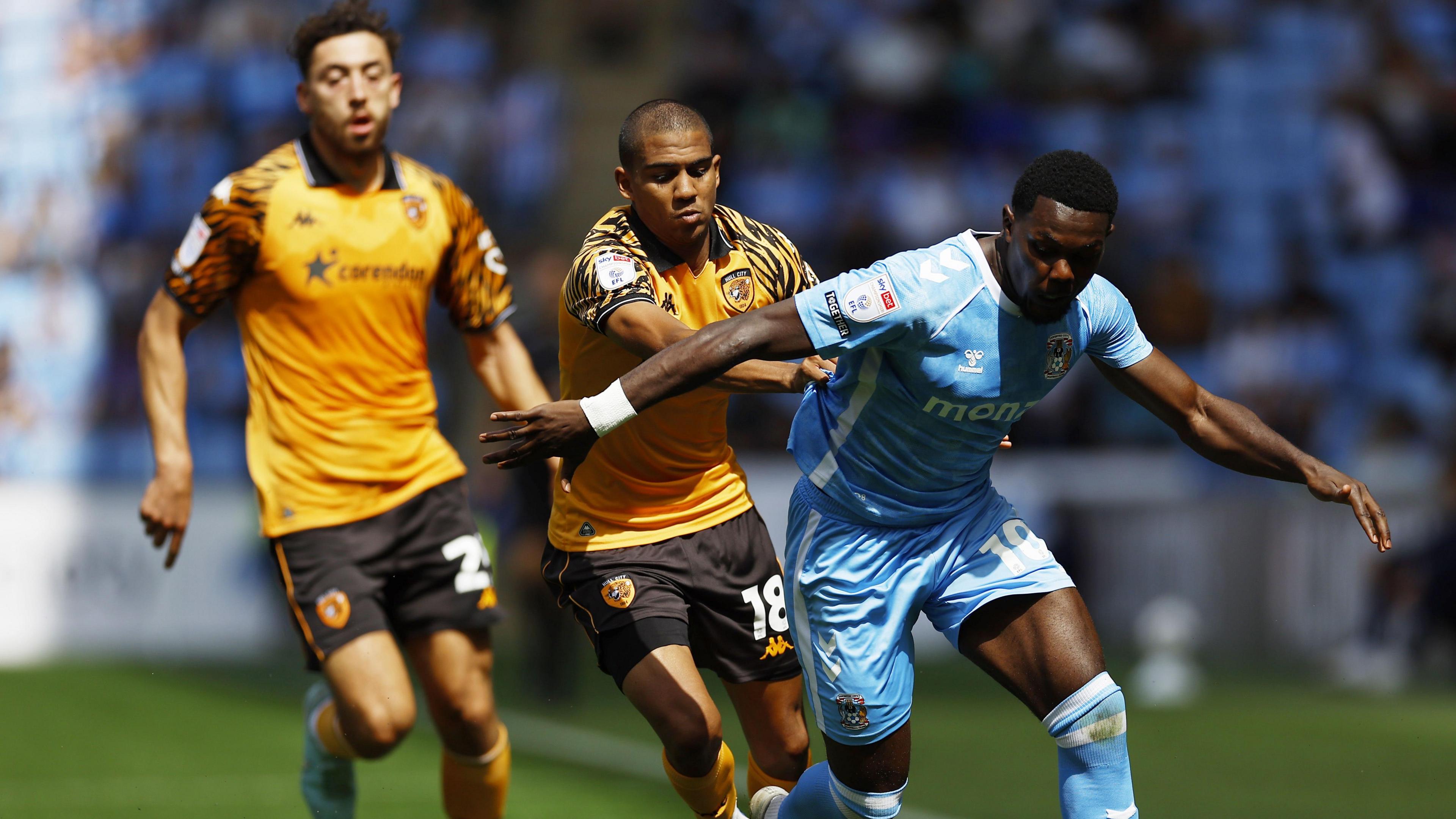 Coventry's Ephron Mason-Clark (right) is pulled back by Hull defender Cody Drameh with Matt Crooks (left) watching on