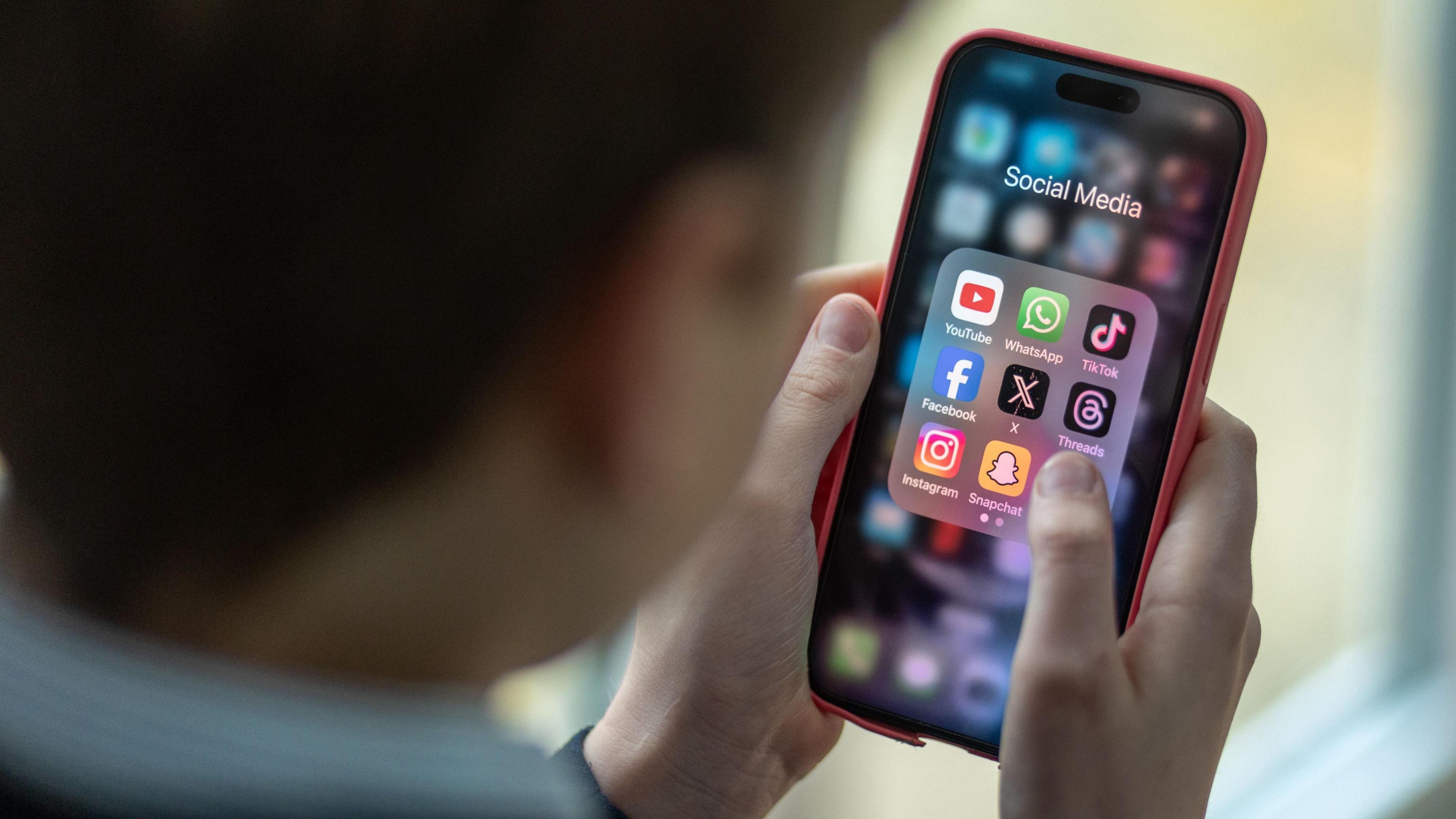 Bachgen ifanc yn gafael Iphone, yn dangos apps cyfryngau cymdeithasol