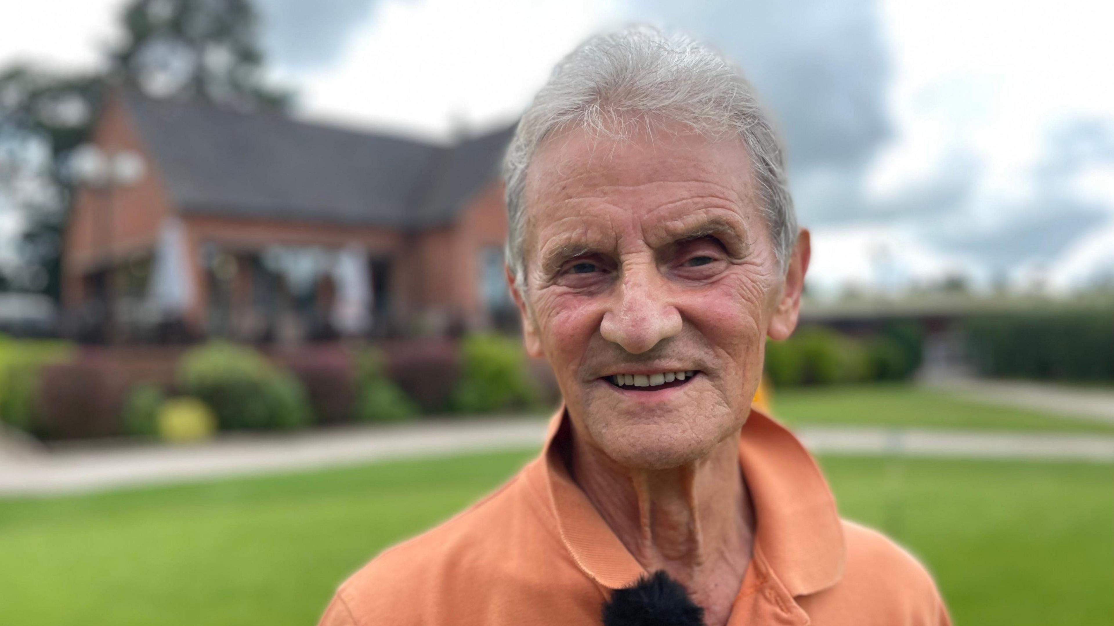 John Payne, who has grey hair, wearing orange shirt