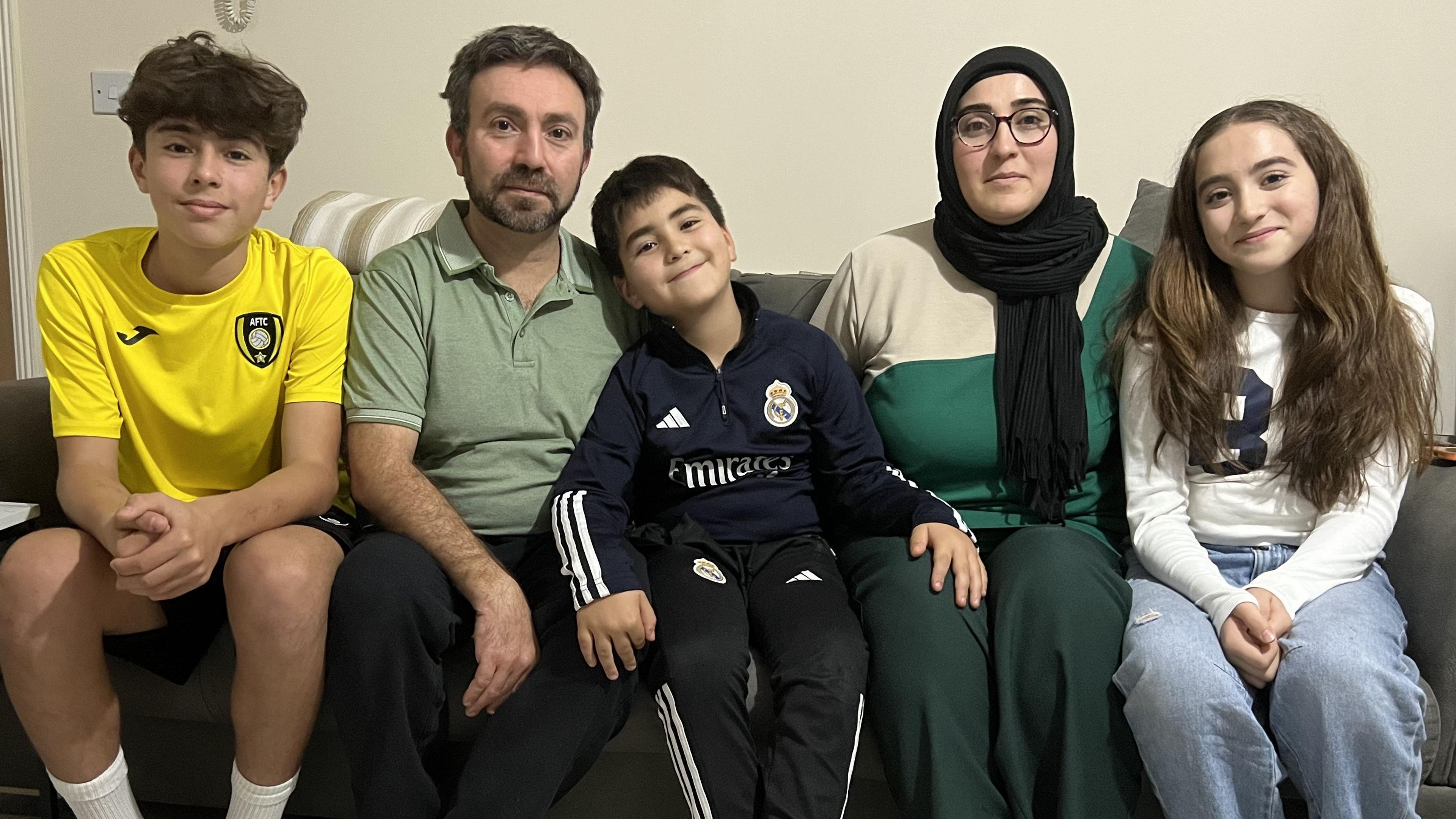 The Olmez family sitting together on their sofa