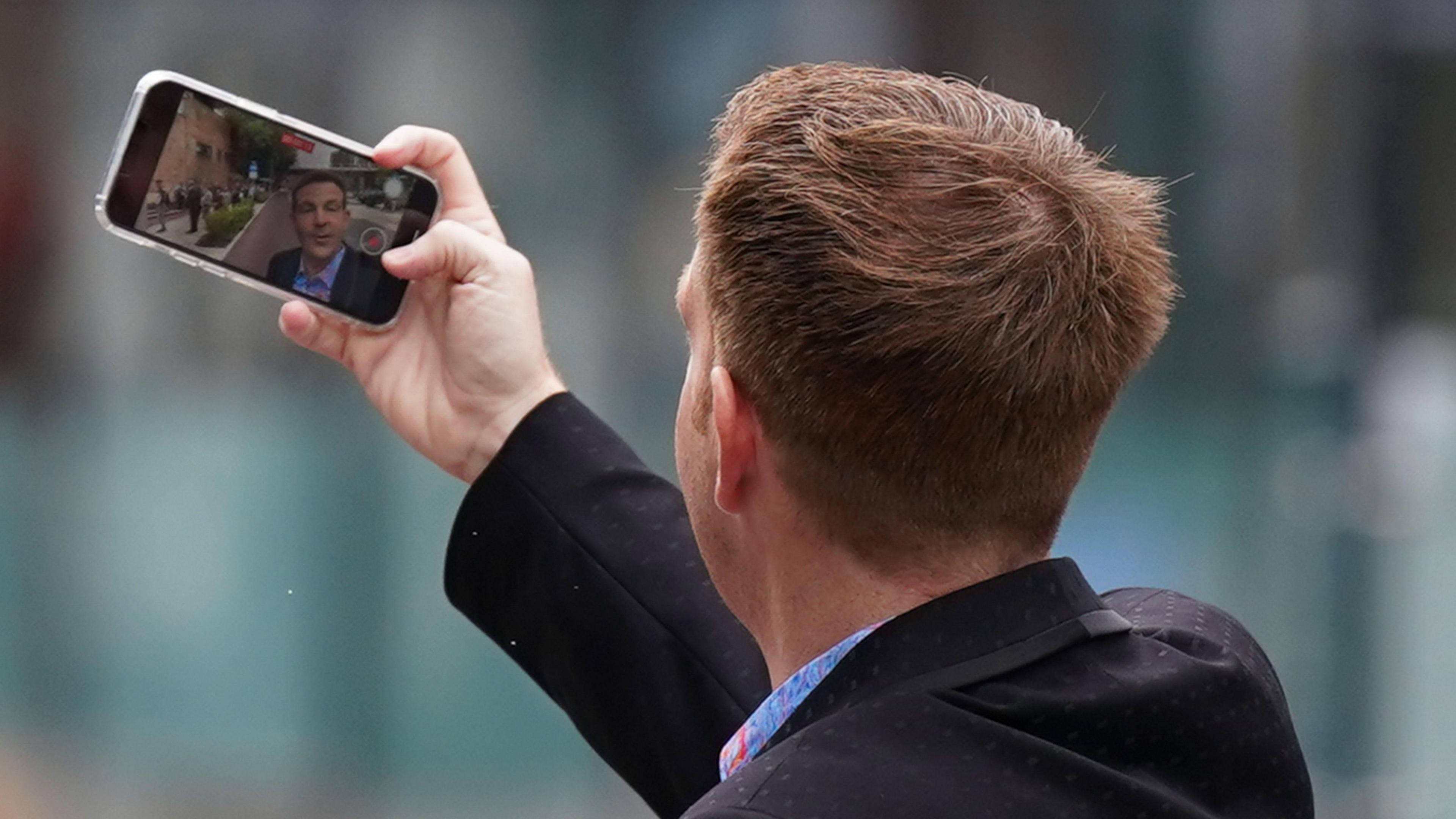 Alex Belfield taking a picture of himself outside Nottingham Crown Court during his trial in July 2022.