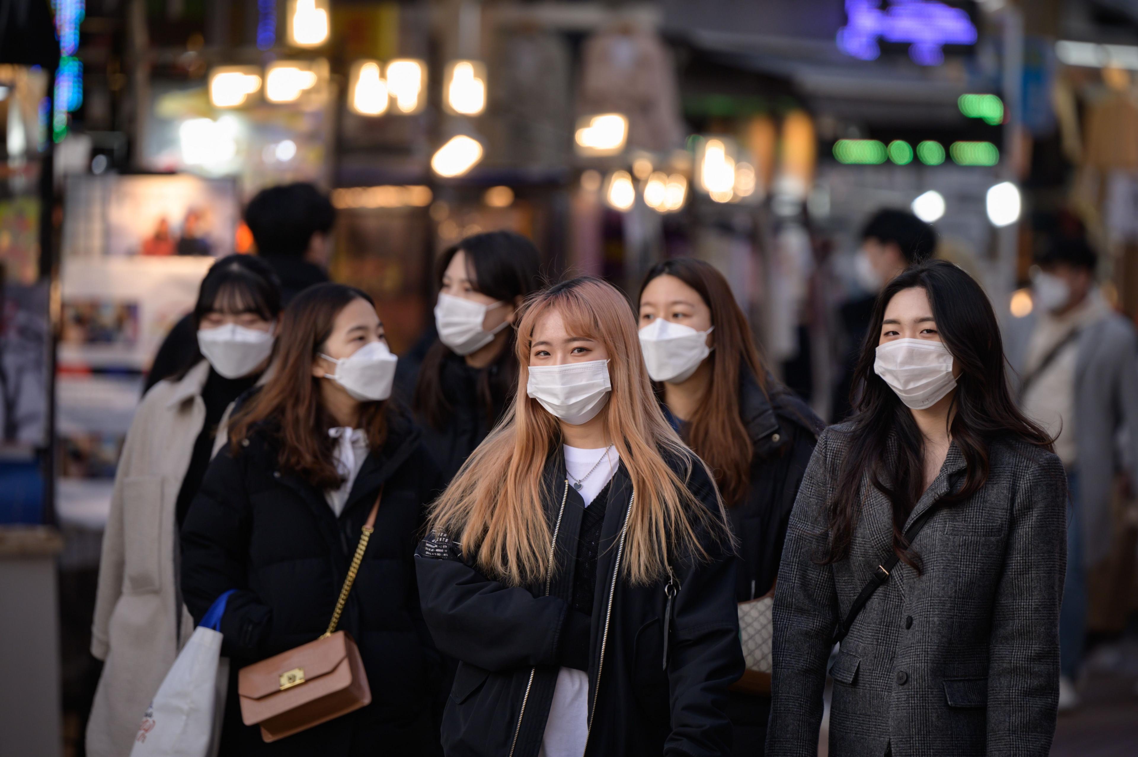 Women wearing face masks walk in a street