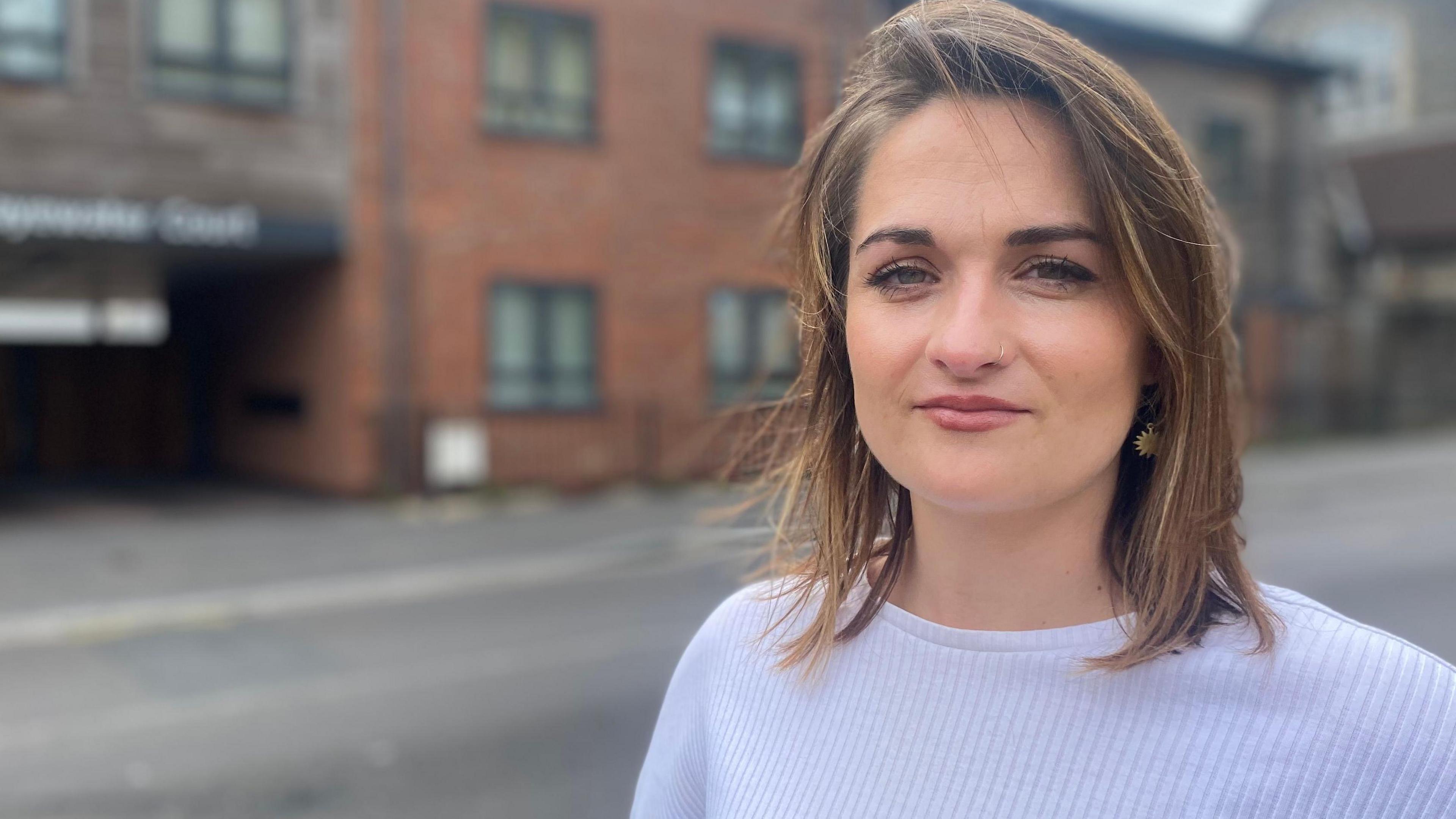 Lucy Tissington in a white top, standing outside Clayewater Court, which is blurred in the background