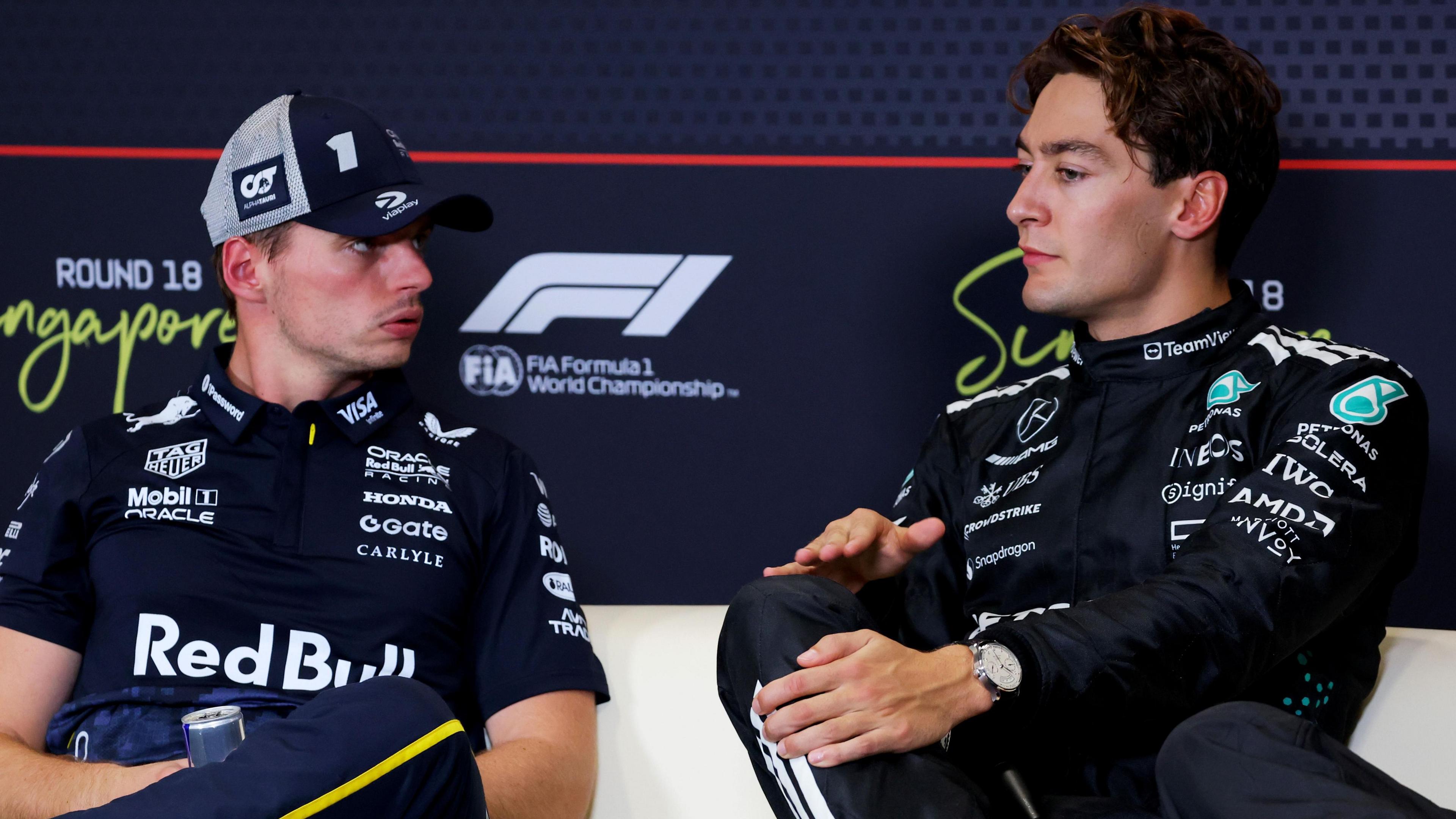 Max Verstappen and George Russell speaking to each other during a news conference at the 2025 Singapore Grand Prix