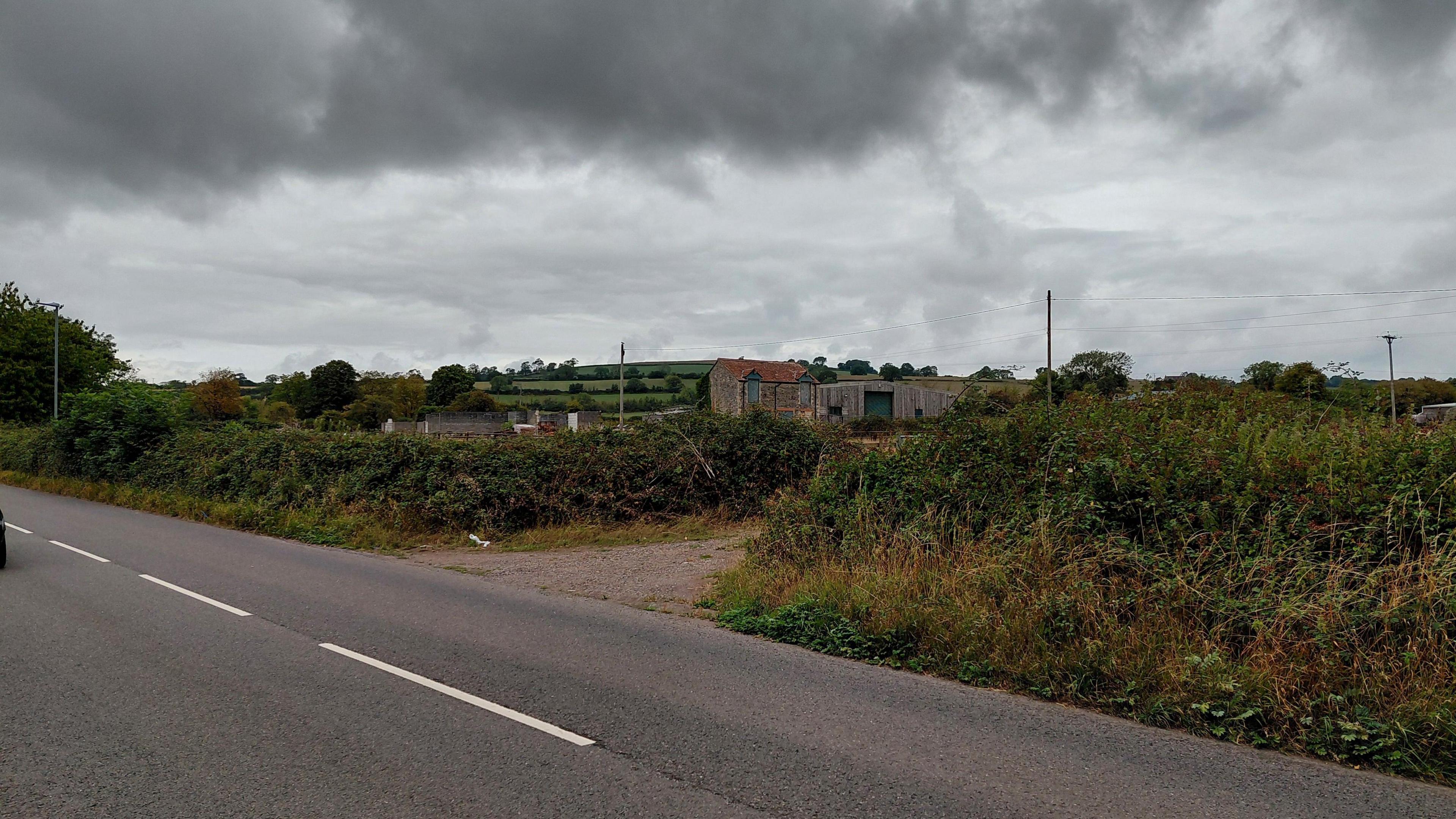 A view from the road of the farmland on a very overcast day.