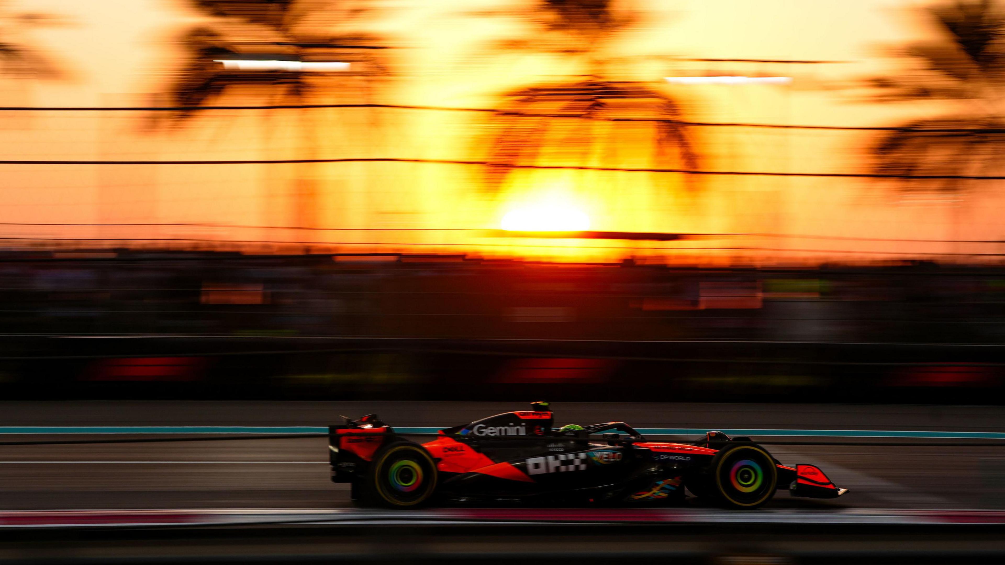 A Formula 1 car speeding past with palm trees in the background