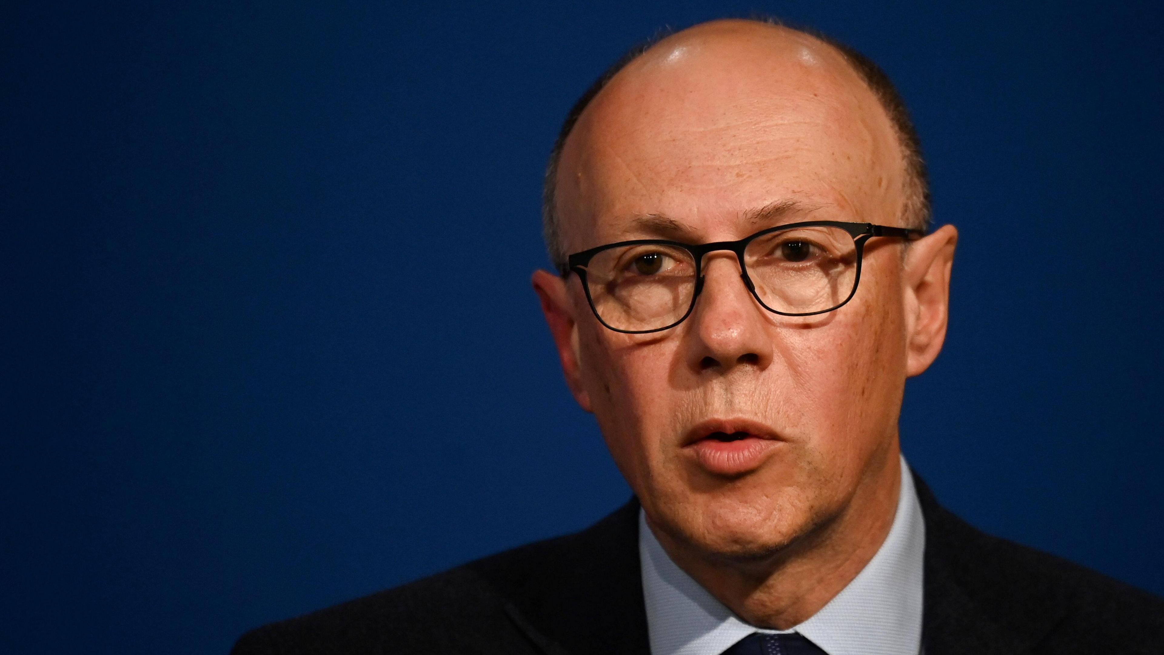 NHS England National Medical Director Professor Sir Stephen Powis is photopraphed wearing a dark suit and tie with a pale shirt. He wears glasses.