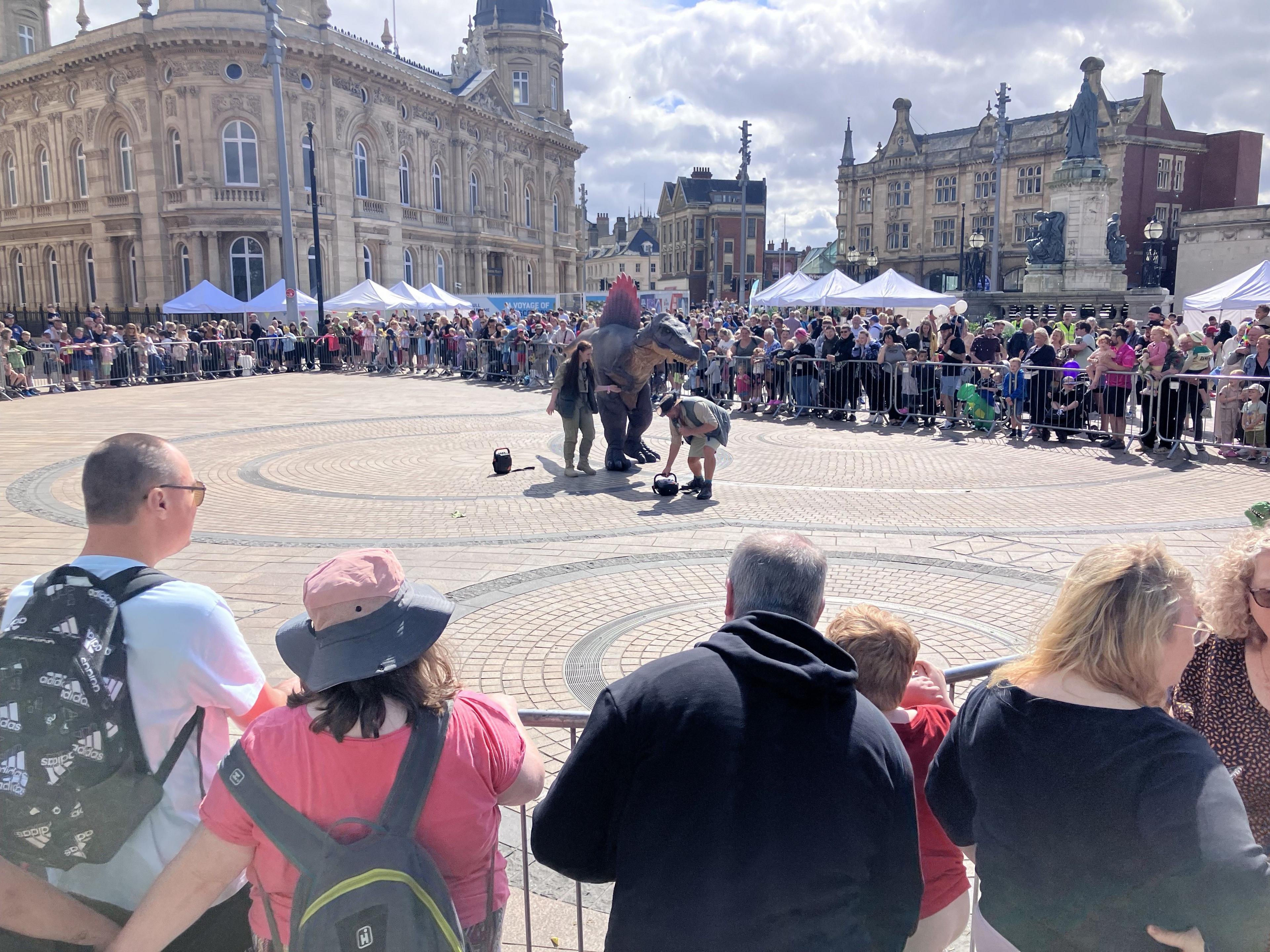 Two park ranger characters flank a spinosaurus as they talk about dinosaurs with the crowds.