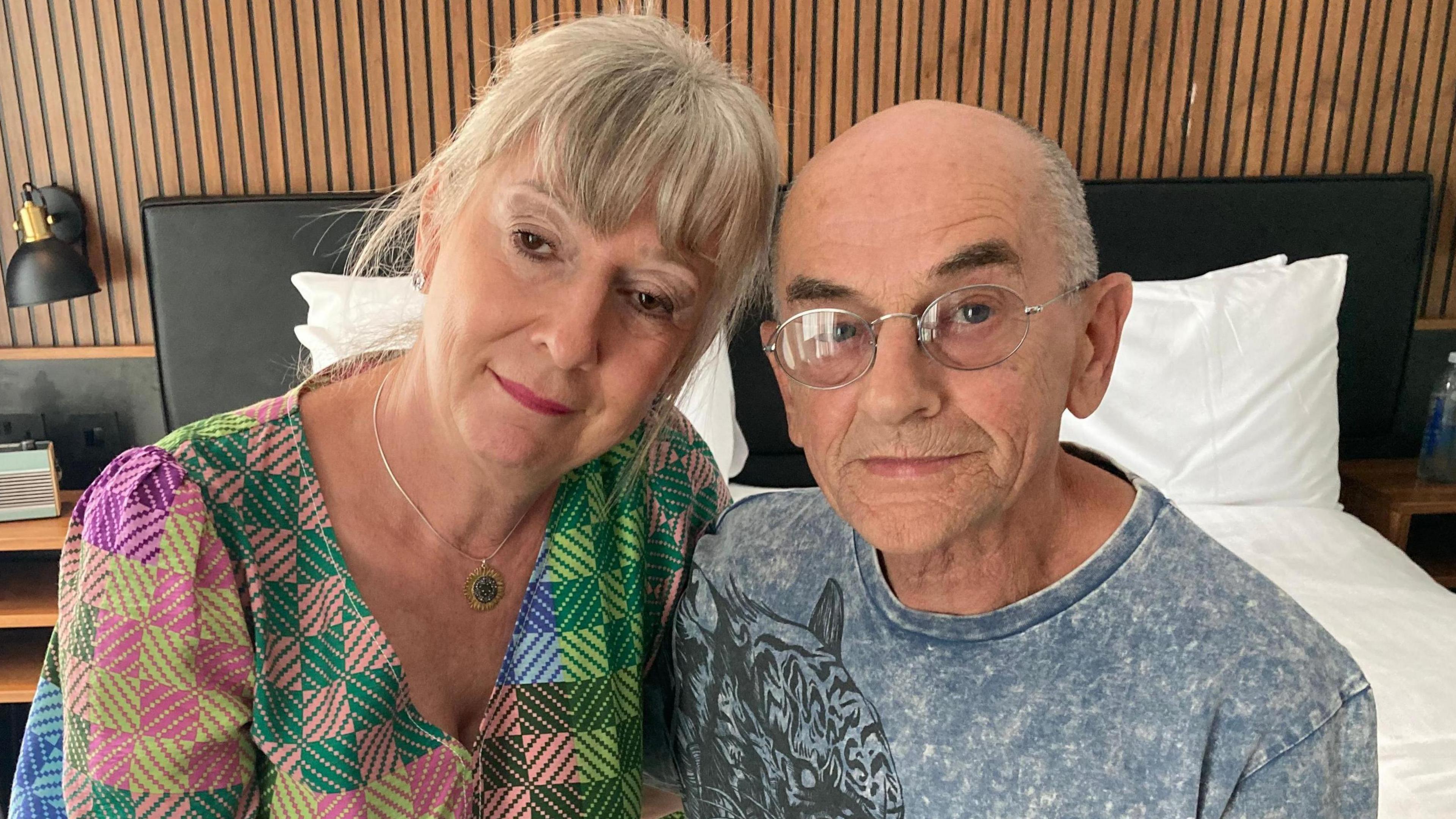 Karen McGory, wearing a multi-coloured top, is sitting next to Colin MCGrory, who is wearing a grey T-shirt with a tiger pattern on it.