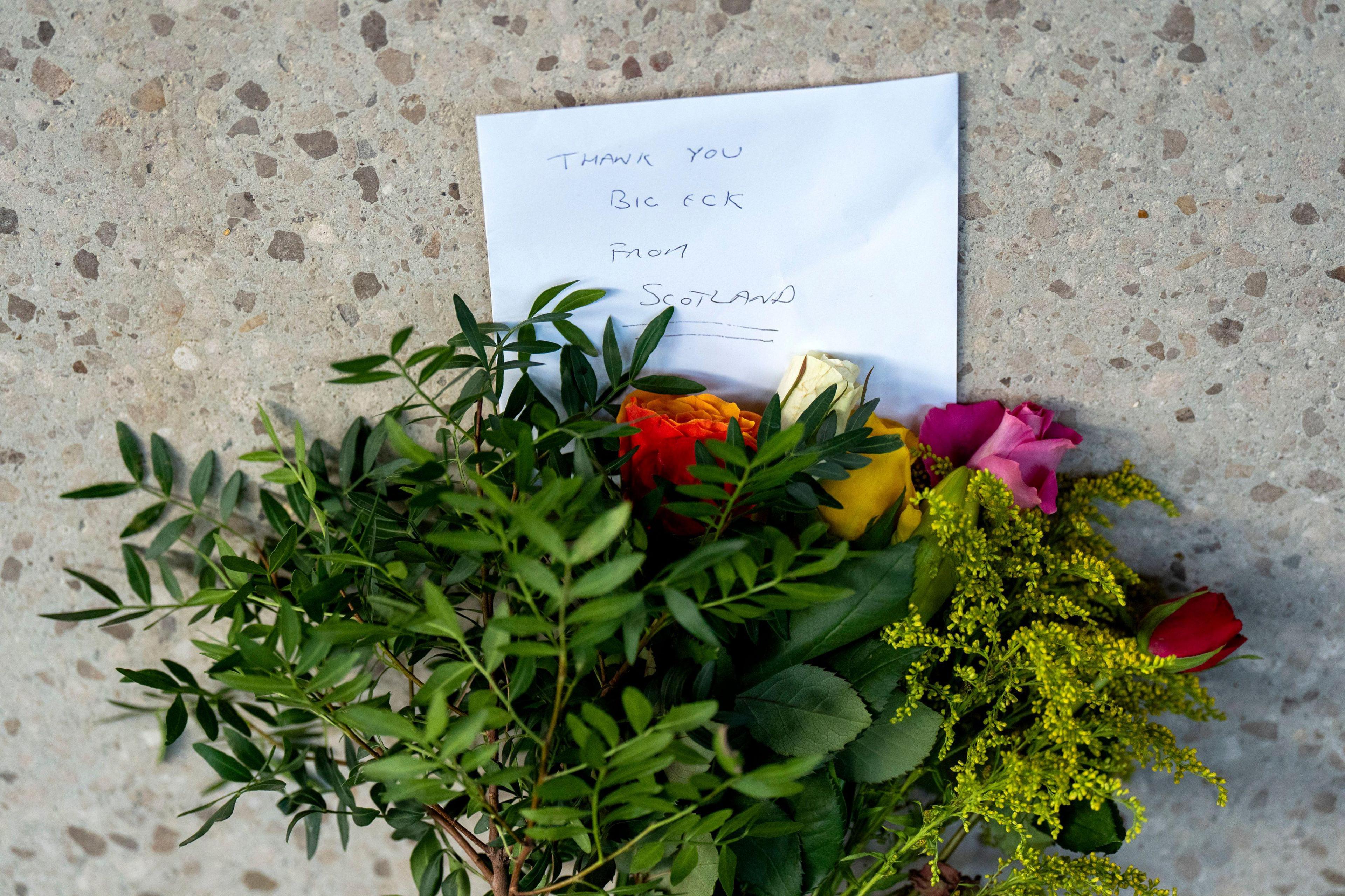 Floral tributes to Salmond fixed to a wall outside the Scottish Parliament building in Edinburgh