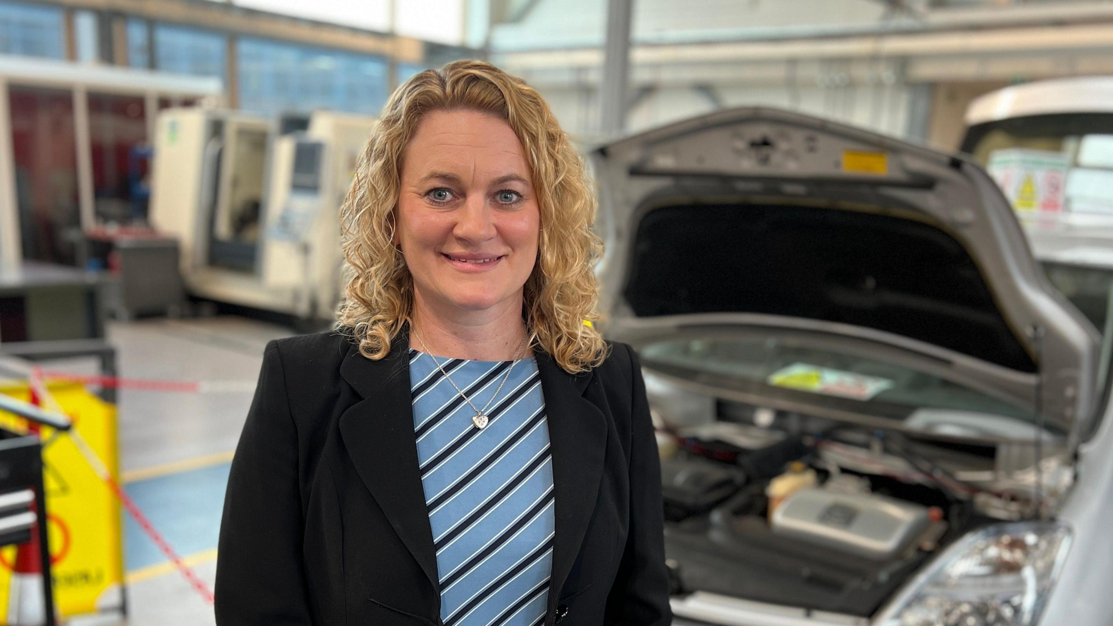 Louise McKinlay posing in front of an open car bonnet at a technical college.