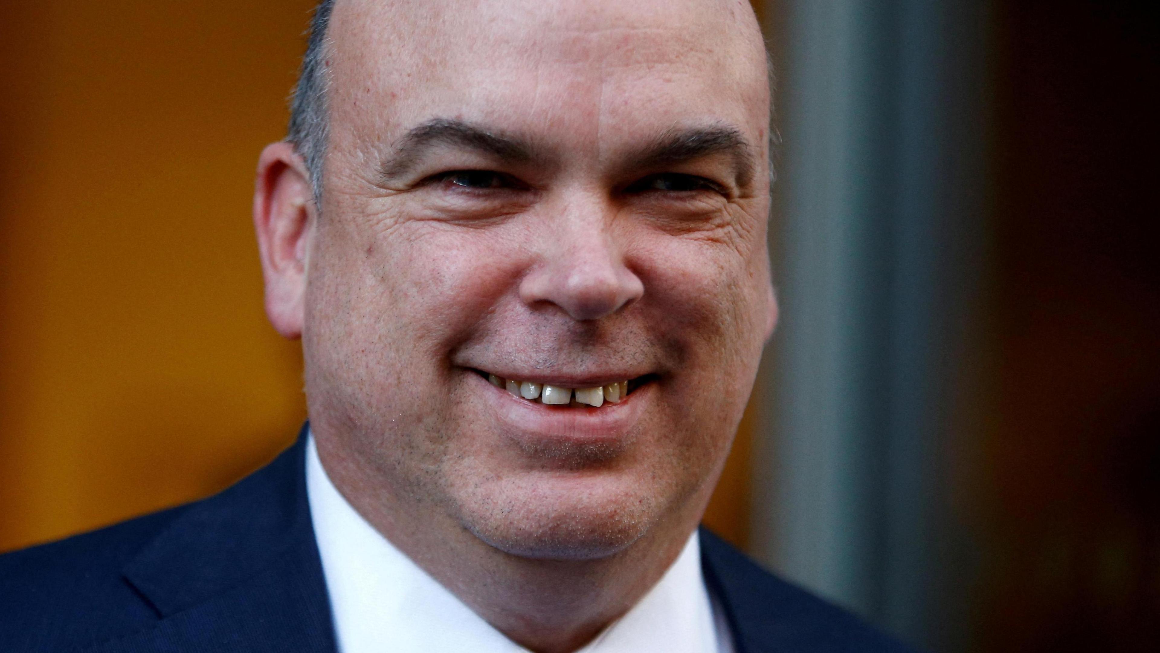 Mike Lynch smiles in a close up photo of him. He's wearing a blue suit with a crisp white shirt.