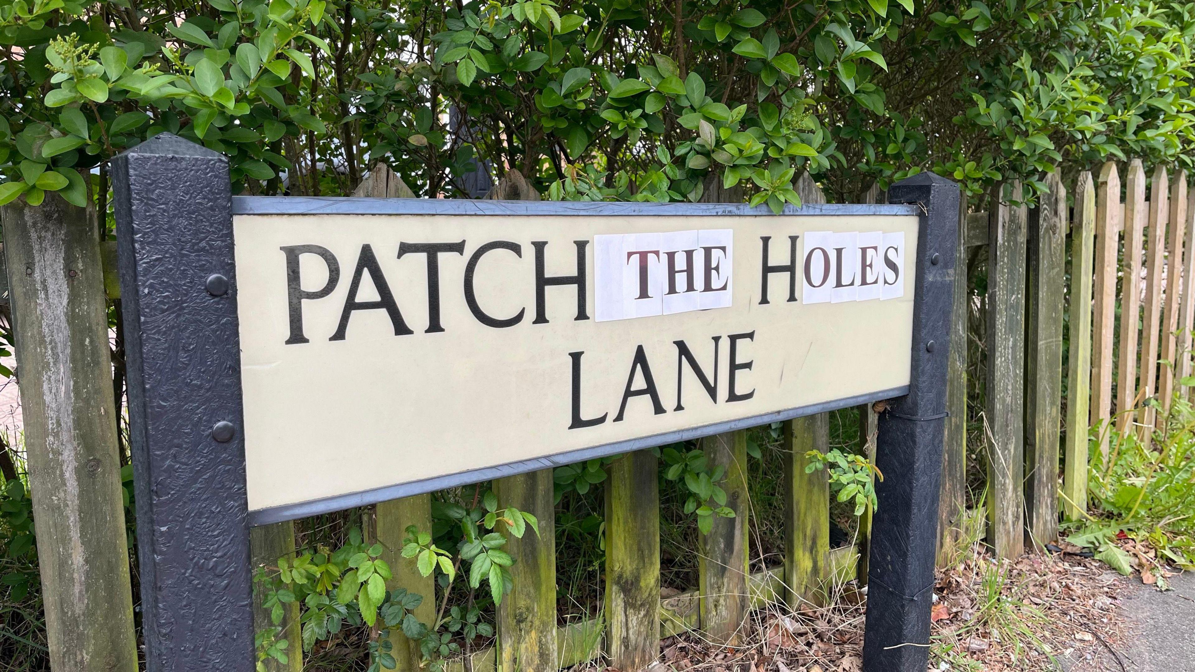 A road sign that reads: "Patch the holes lane"