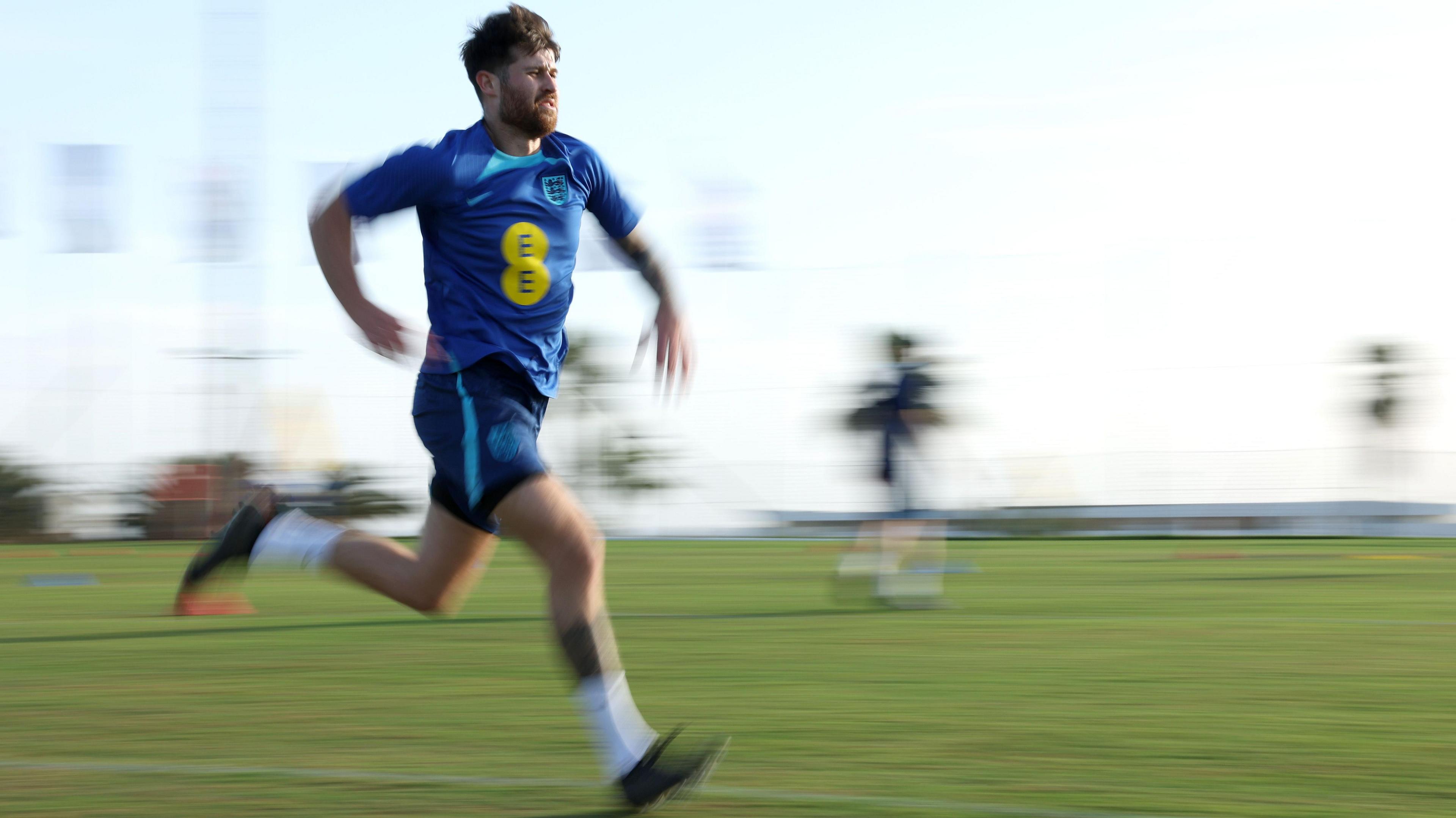 A picture of Harry running in his blue England kit, with the background blurred 