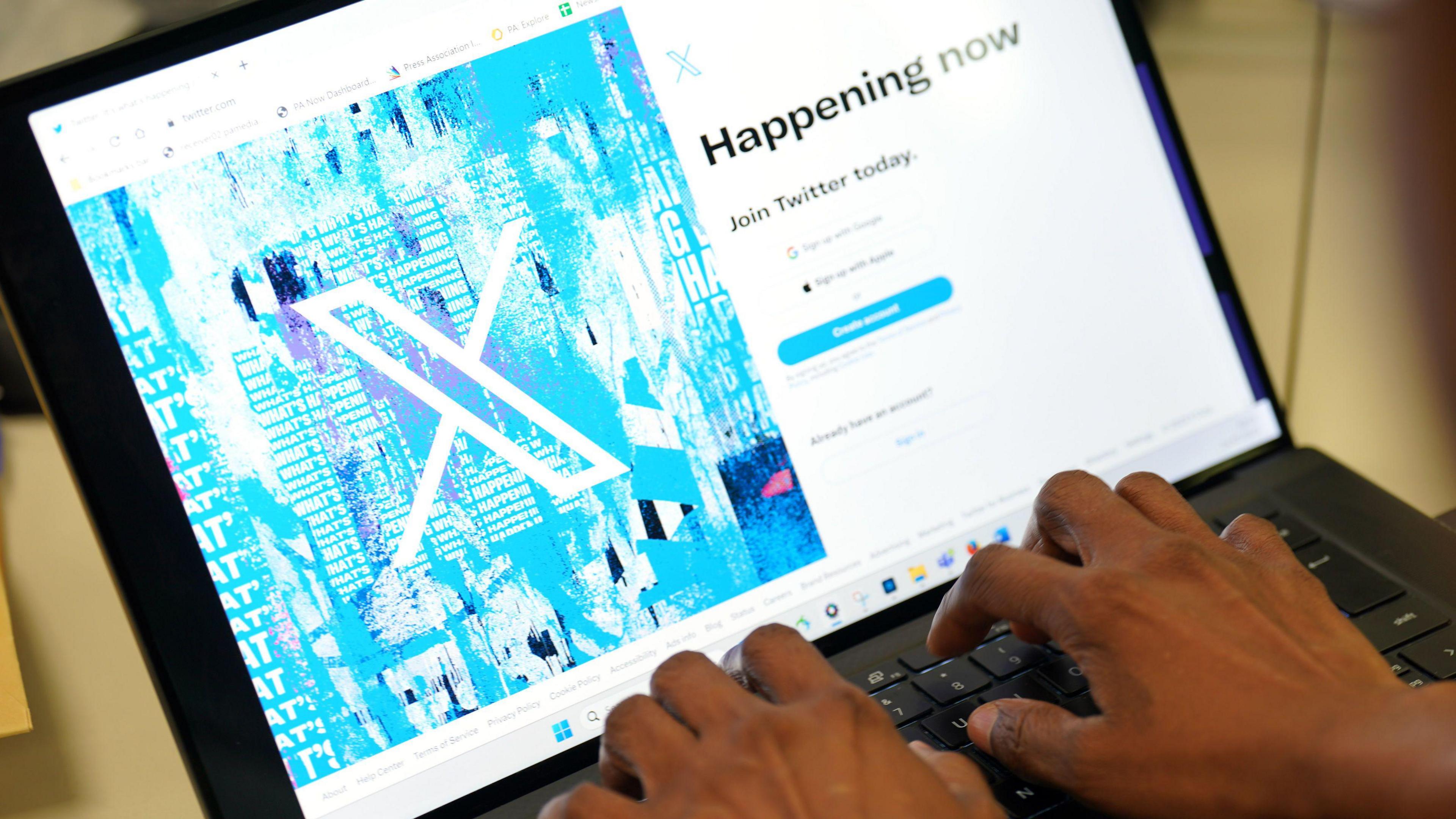 Person logging on to X website on laptop computer