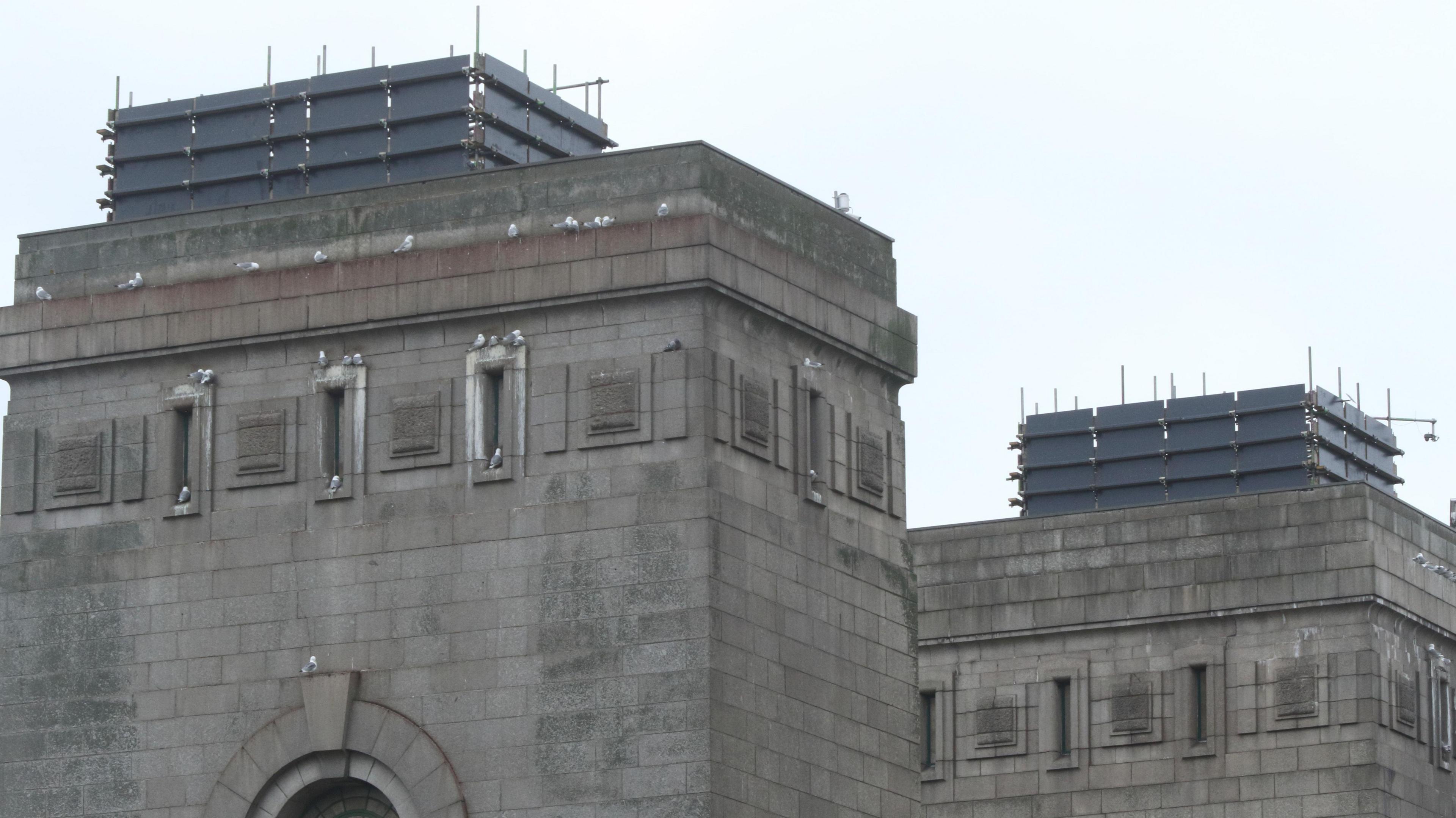 Two scaffolding units covered in dark sheeting on top of two of the Tyne Bridge's towers