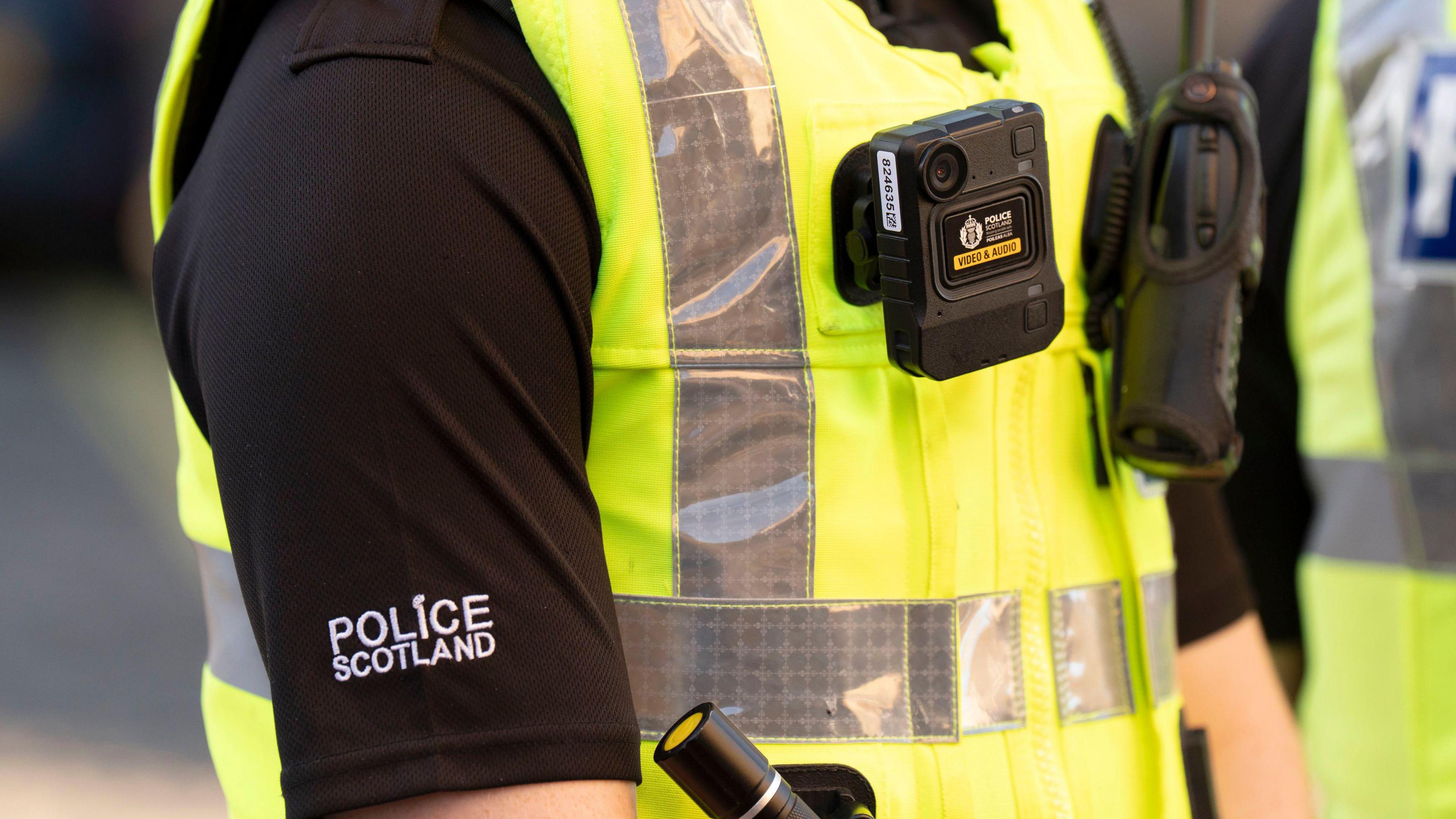 A police Scotland officer wearing a black t-shirt and neon police uniform.