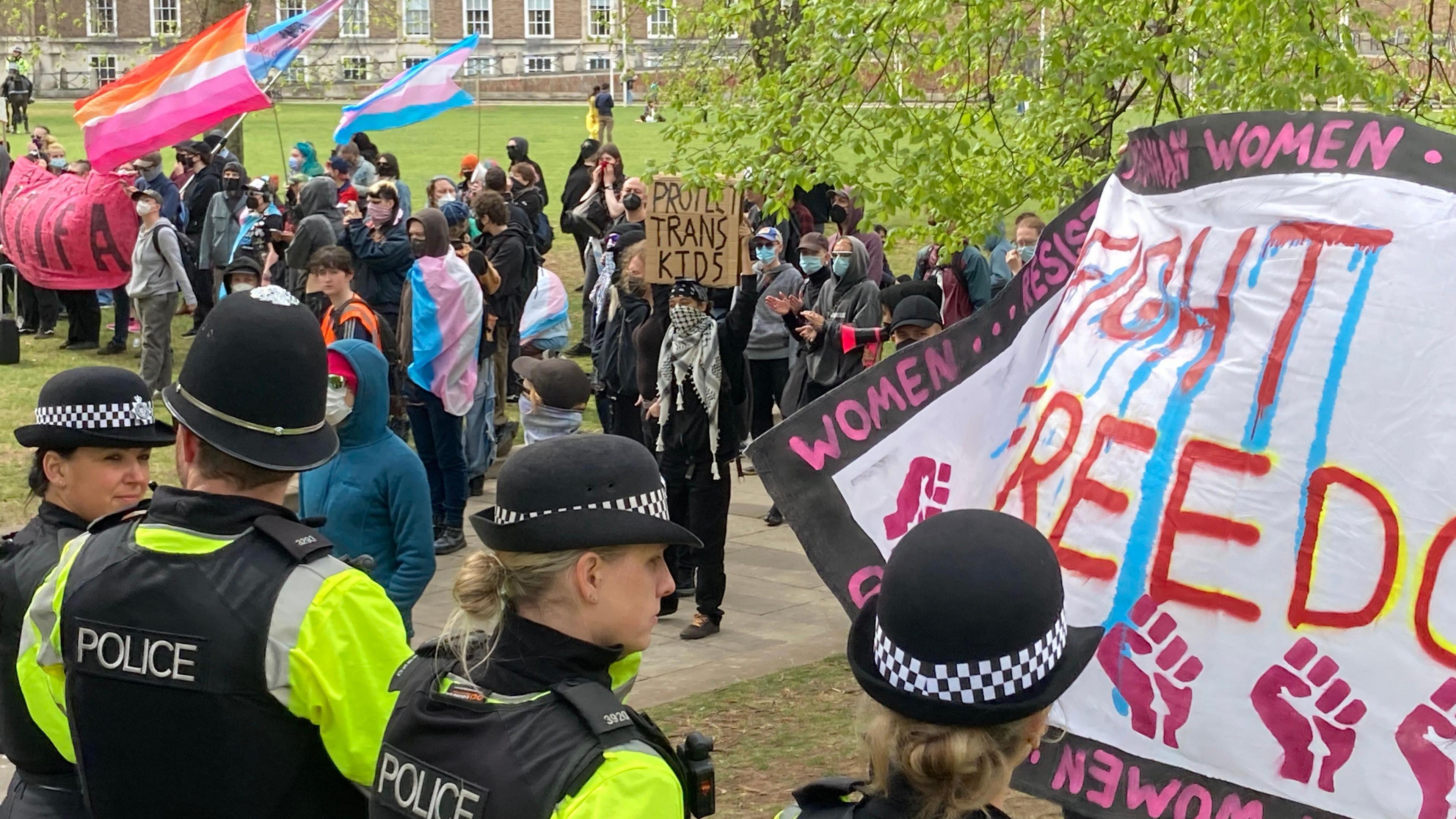 A line of police in front of counter protestors supporting the transgender community