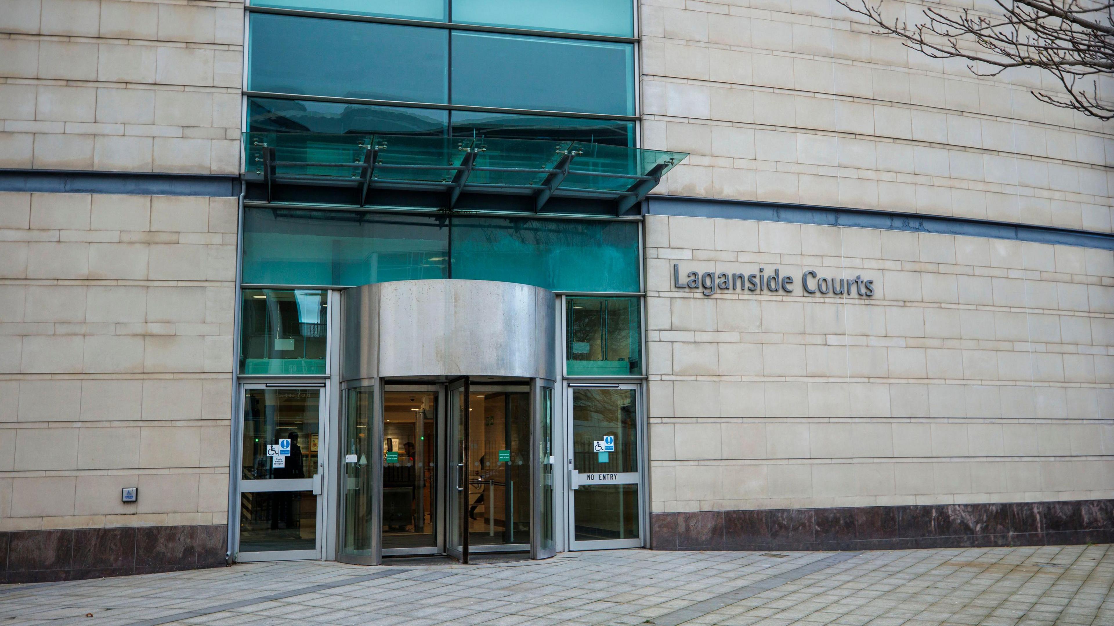 The outside of Laganside Court shows glass doors, a pale wall and empty path. 