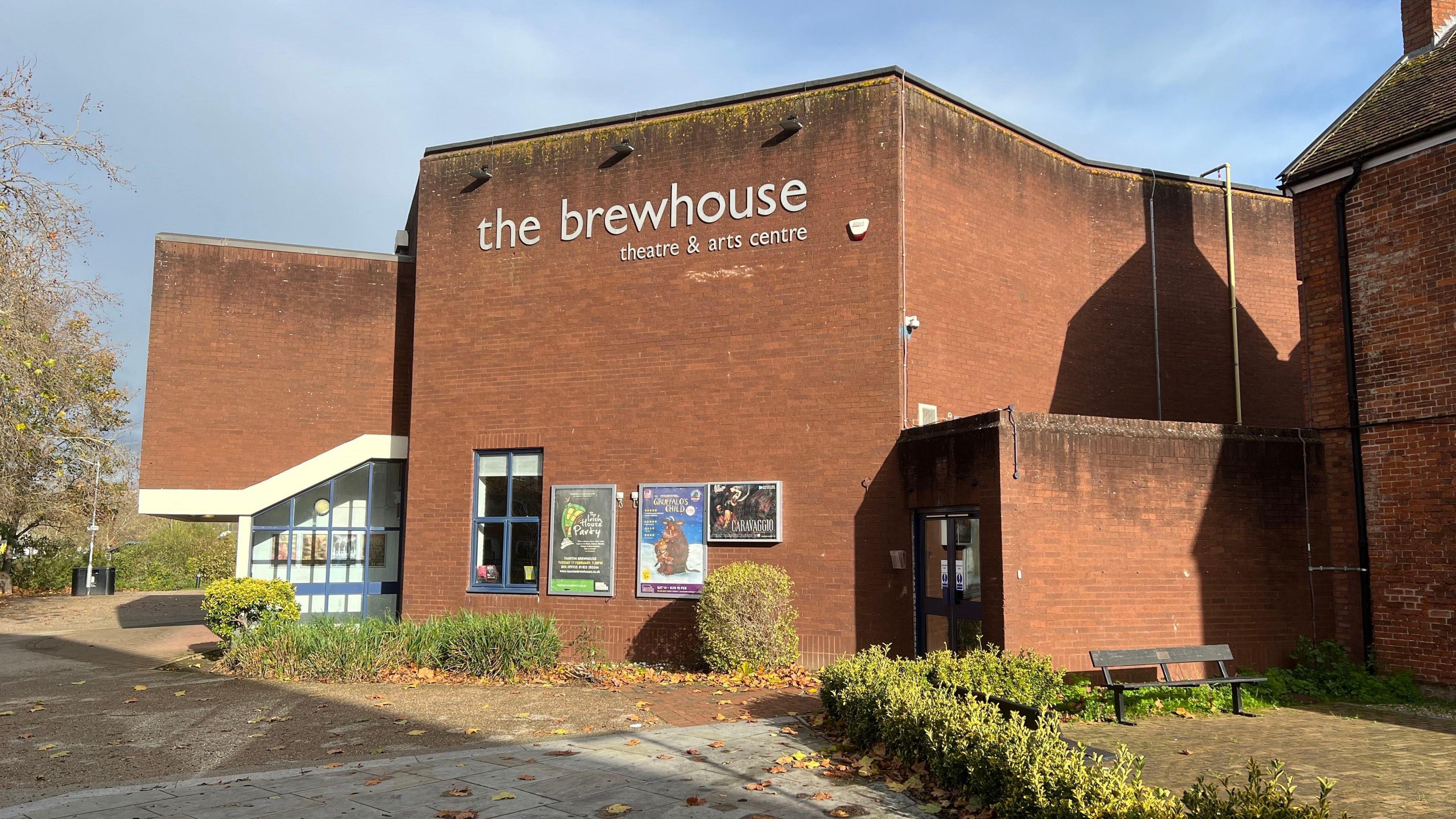 The exterior of the Brewhouse Theatre. It's made of brown brick and has posters on the outside advertising upcoming shows. 