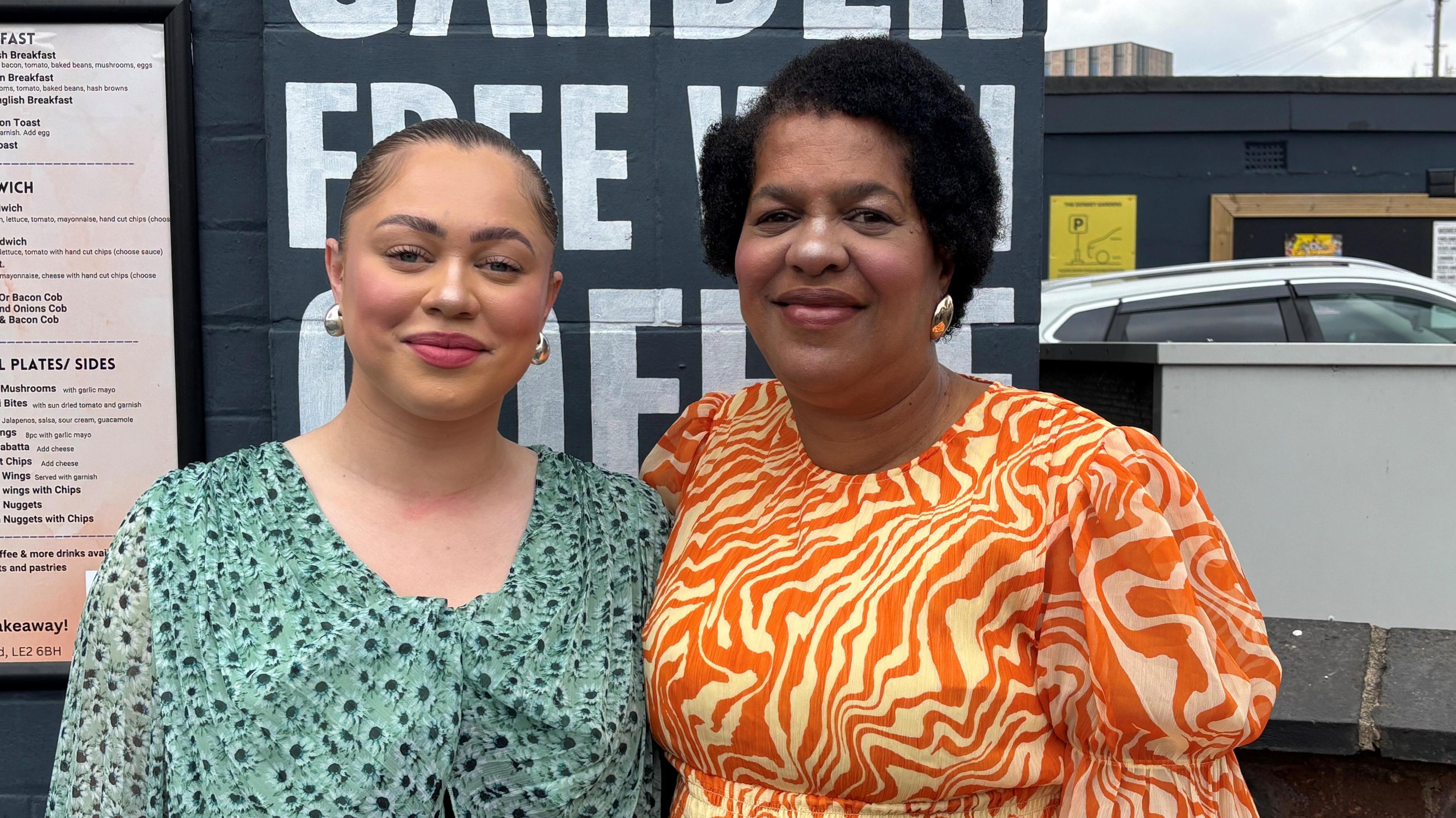 Amber Stephens wearing a blue/green flowery dress with her mother Karlene Stephens in a wavy orange and white dress.