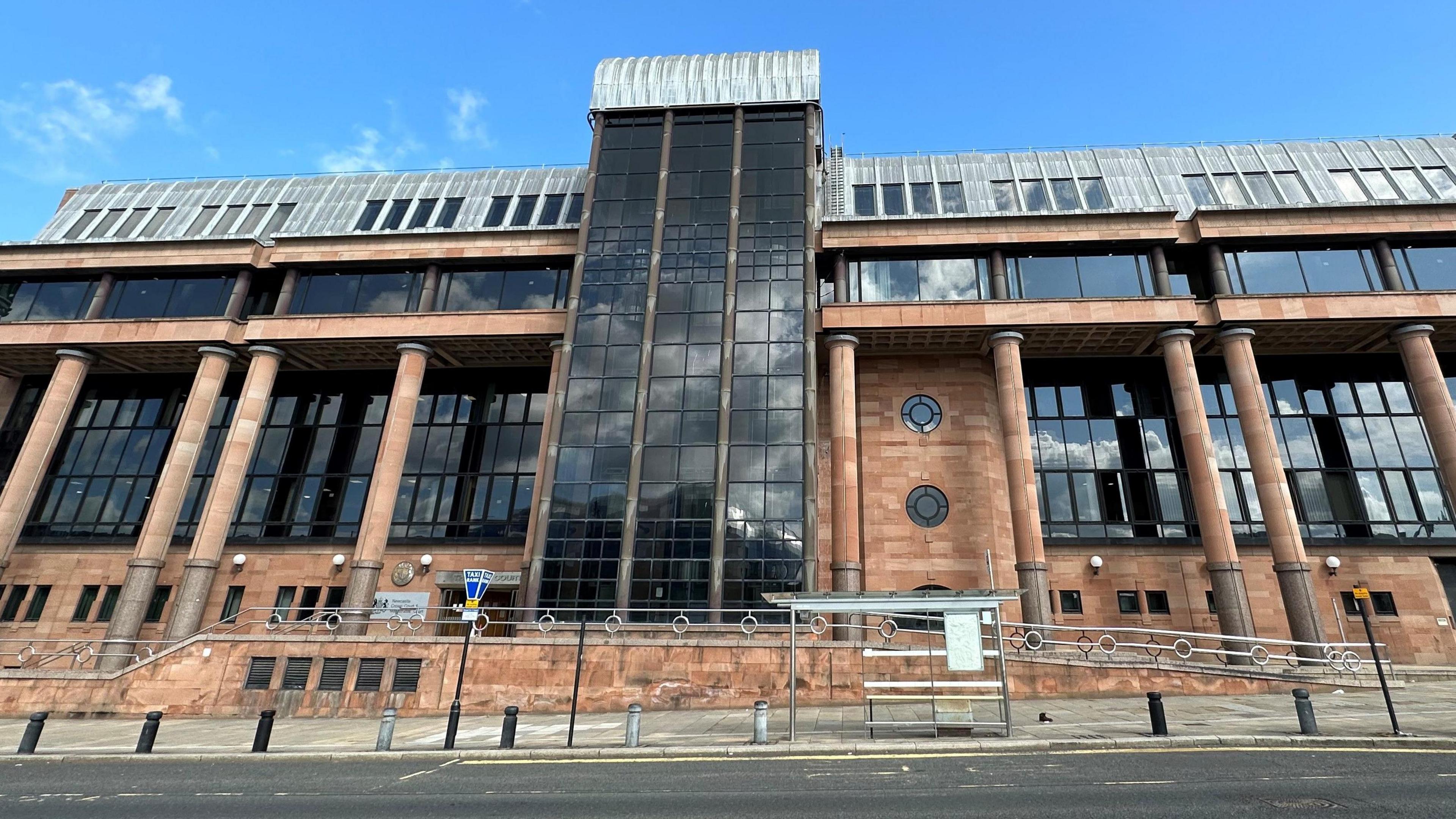 An imposing court building made of red stone and large dark windows.